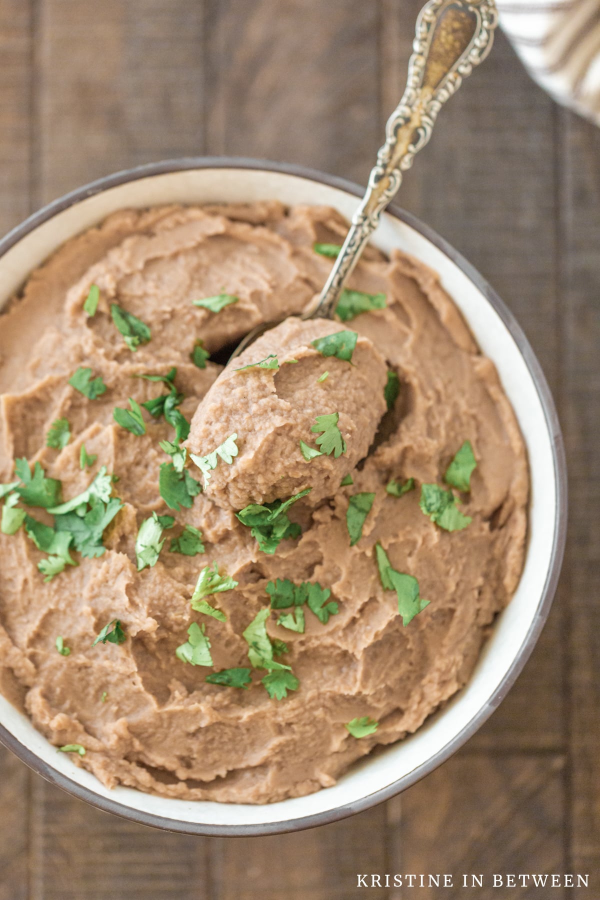 A bowl of refried beans sitting next to a Crock-pot and a small bowl of salsa.