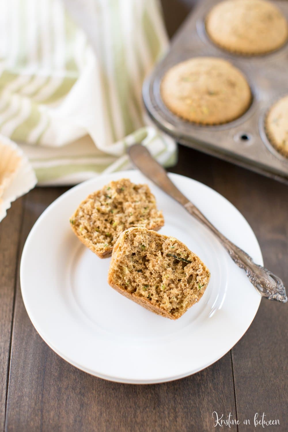 A whole wheat zucchini muffin cut in half to show the spongy texture of the inside of the muffin.