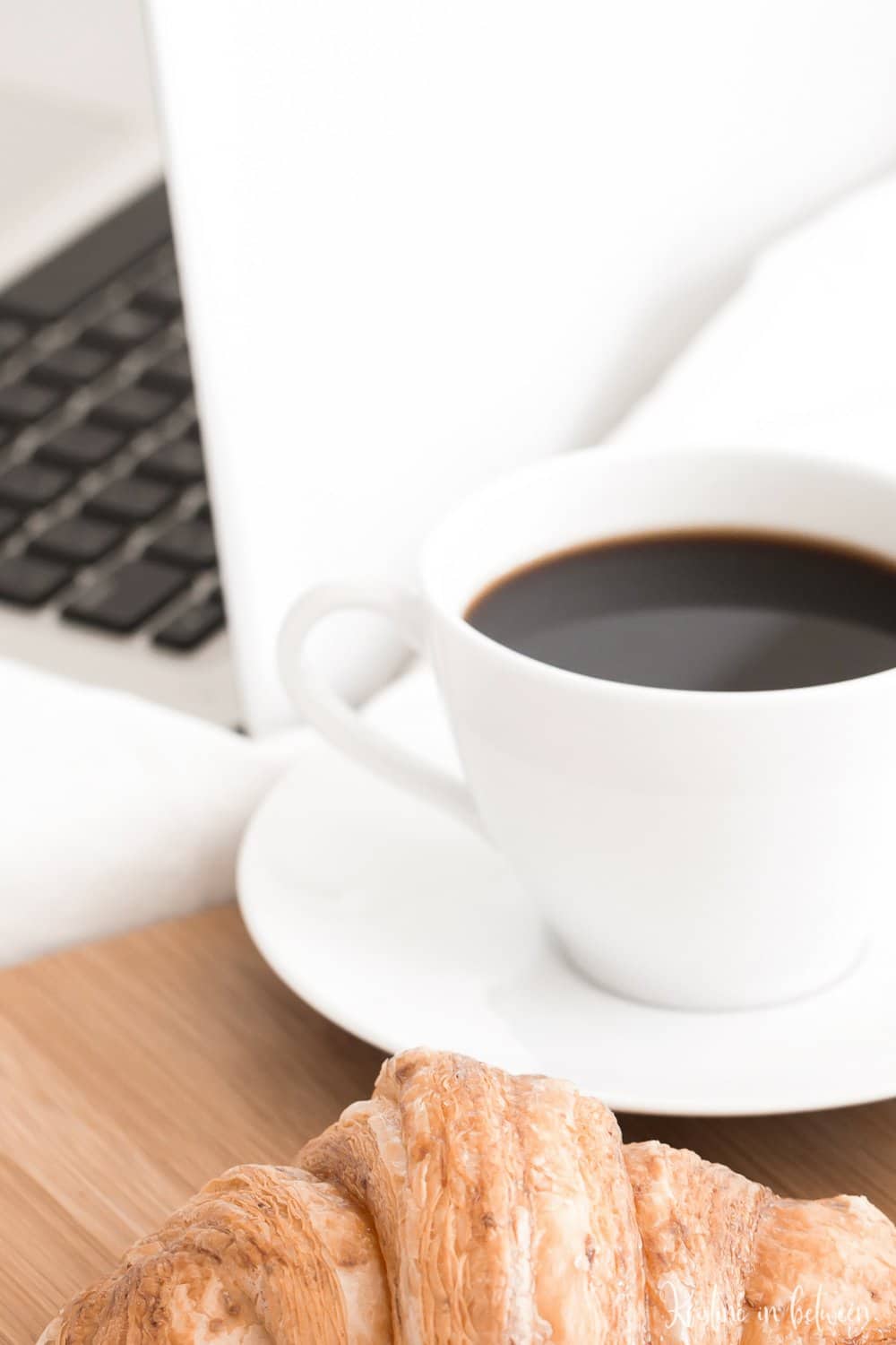 A computer sitting with a cup of coffee.