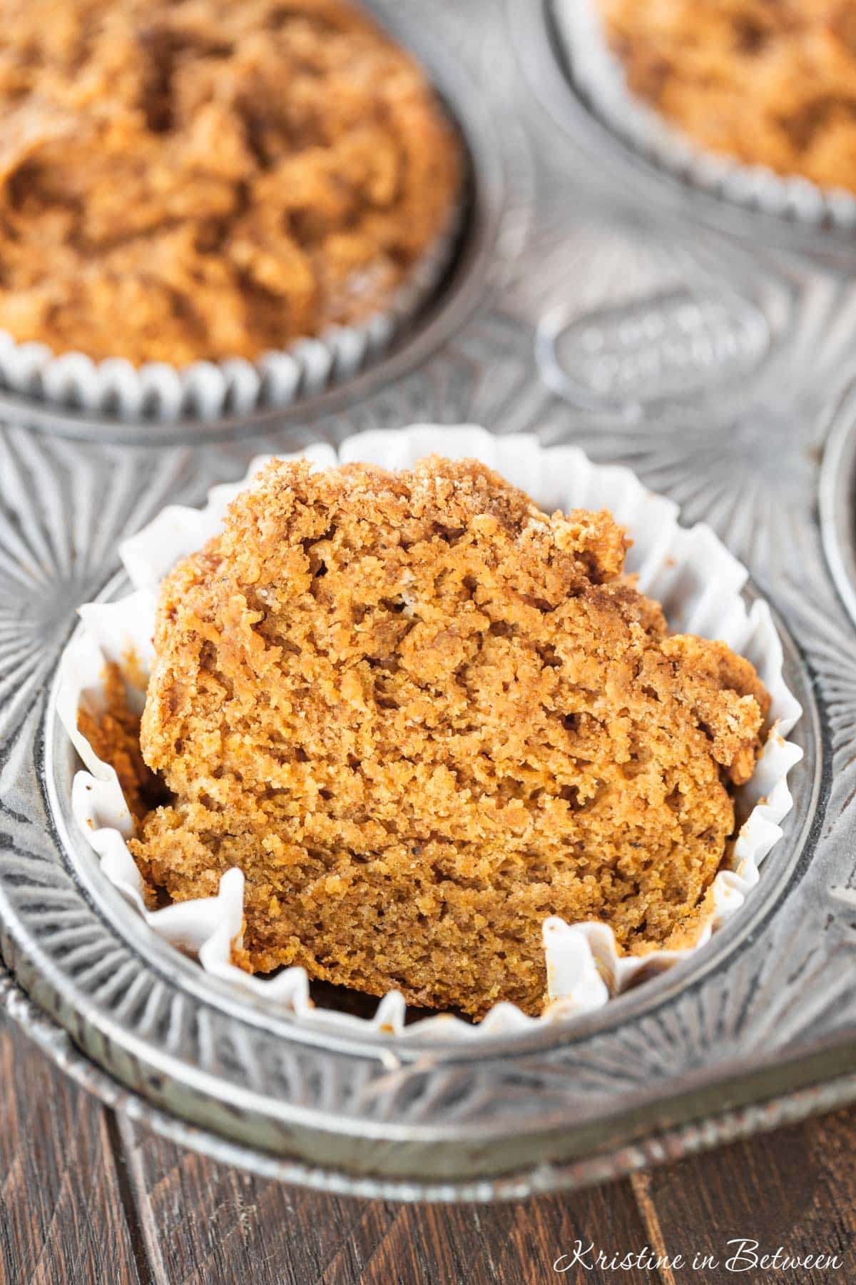 A pumpkin muffin cut in half to show the tender crumb inside.