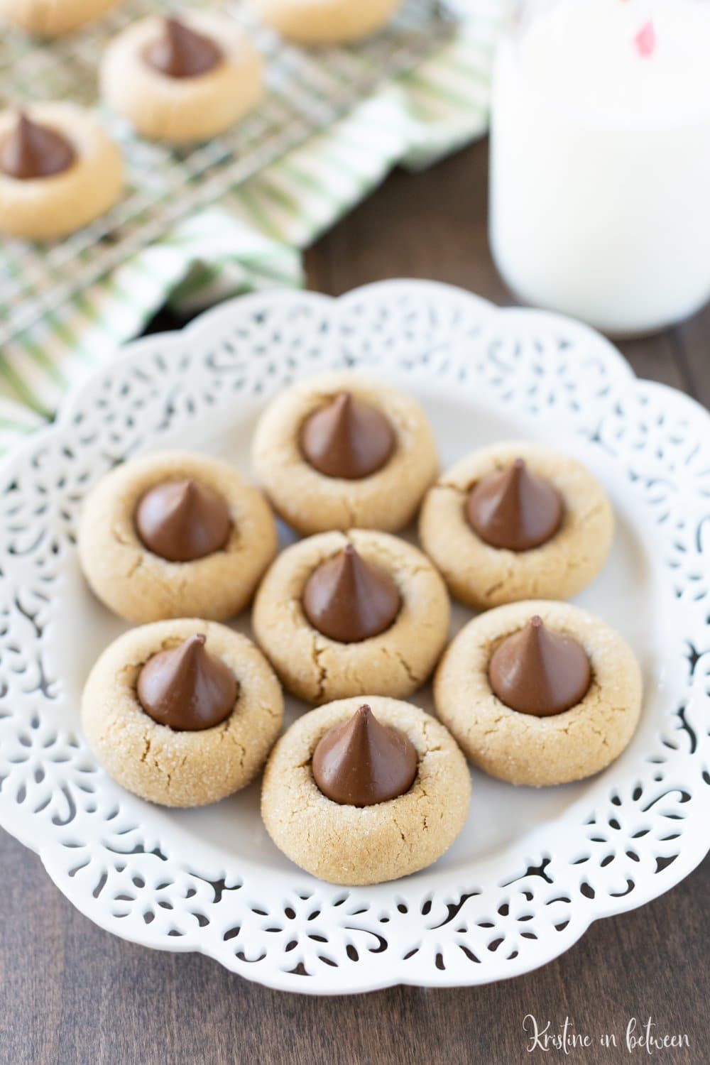 Cookies sitting on a decorative plate with a jar of milk sitting next to them.