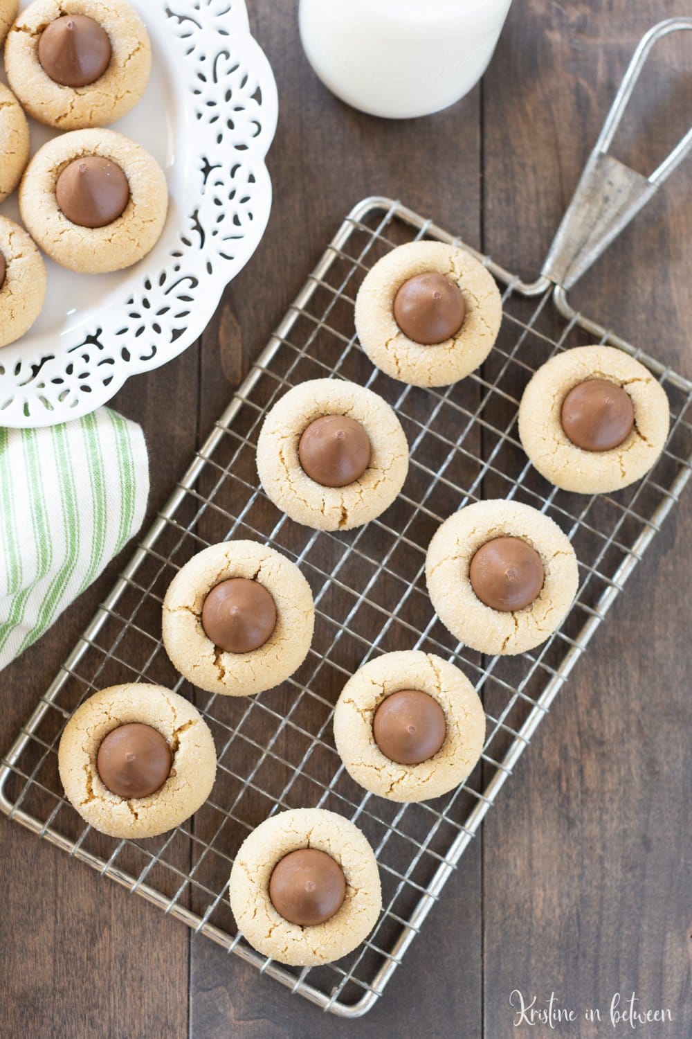 Cookies sitting on a wire rack next to a decorative plate of cookies.