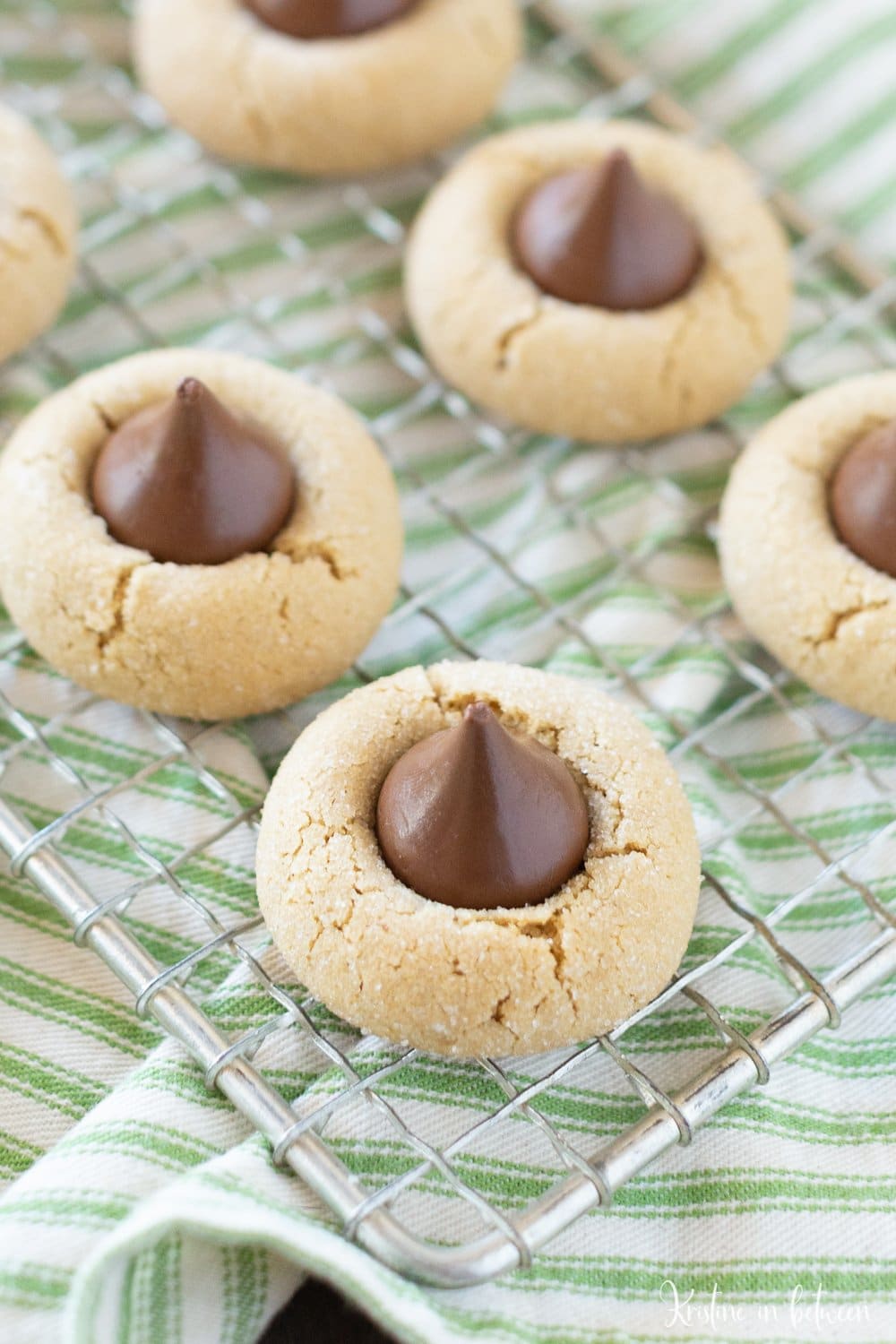 Cookies sitting on a wire rack with a green striped napkin underneath them.