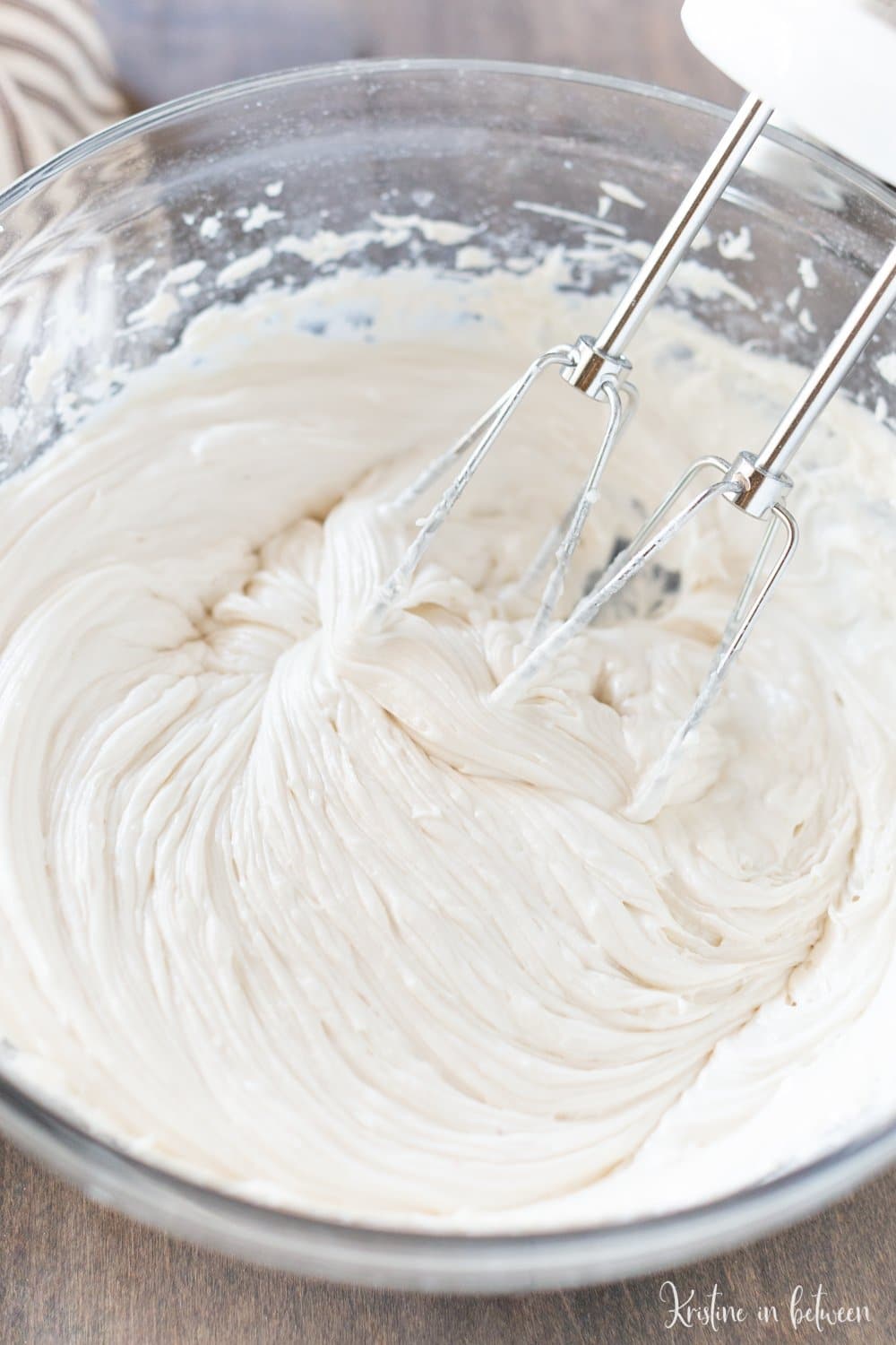 Frosting in a glass bowl with an electric mixer.