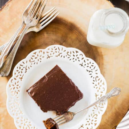 A slice of Texas sheet cake on a white plate with a bite on a fork.