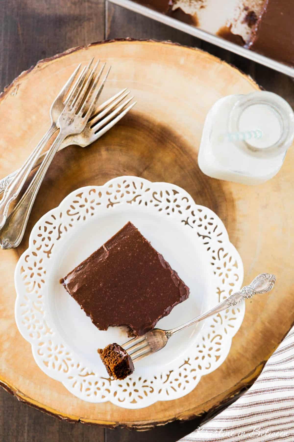 A slice of Texas sheet cake on a white plate with a bite on a fork.
