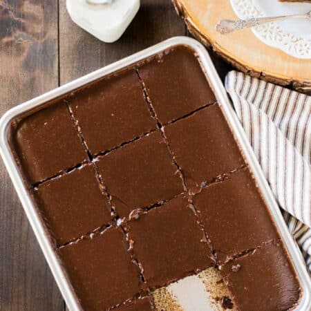 A freshly baked and frosted Texas sheet cake in a small sheet pan with a jar of milk sitting next to it.
