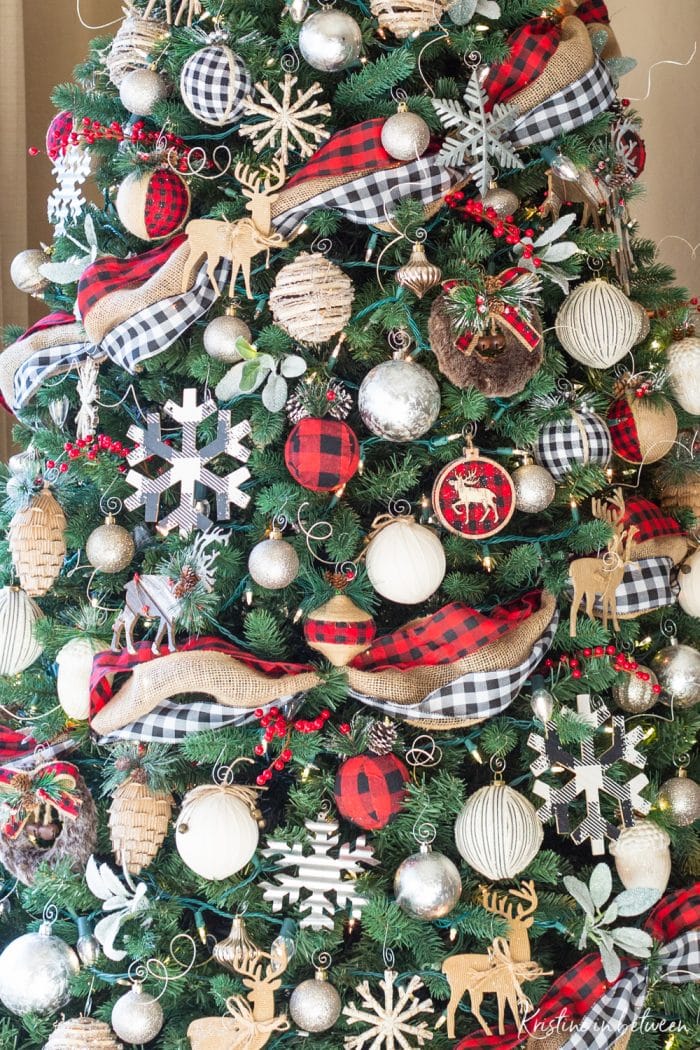 A close up of a decorated Christmas tree in red buffalo check, black and white buffalo check, and rustic snowflakes and cabin animals.
