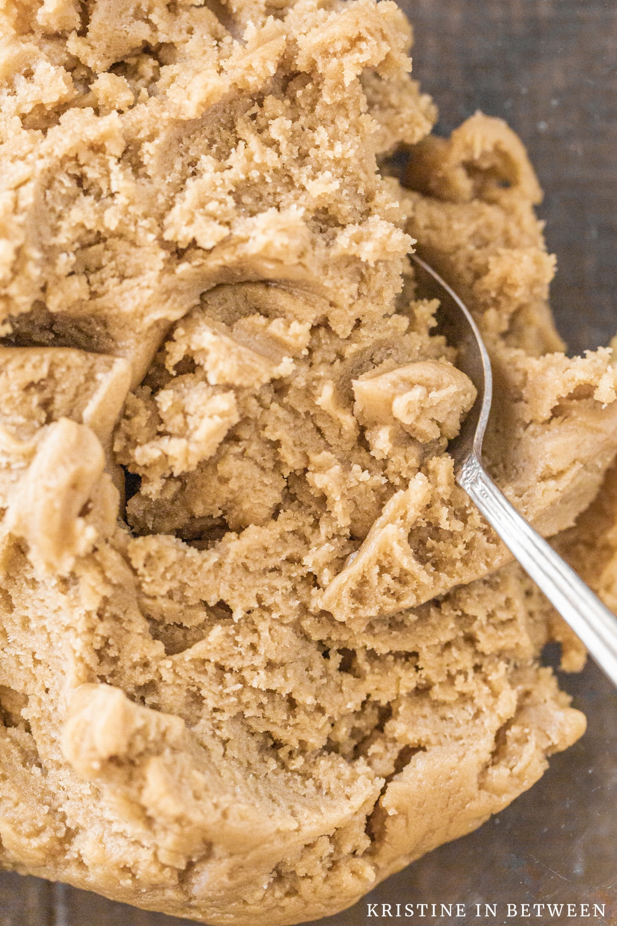 Basic cookie dough mixed up in a glass bowl with an antique spoon.
