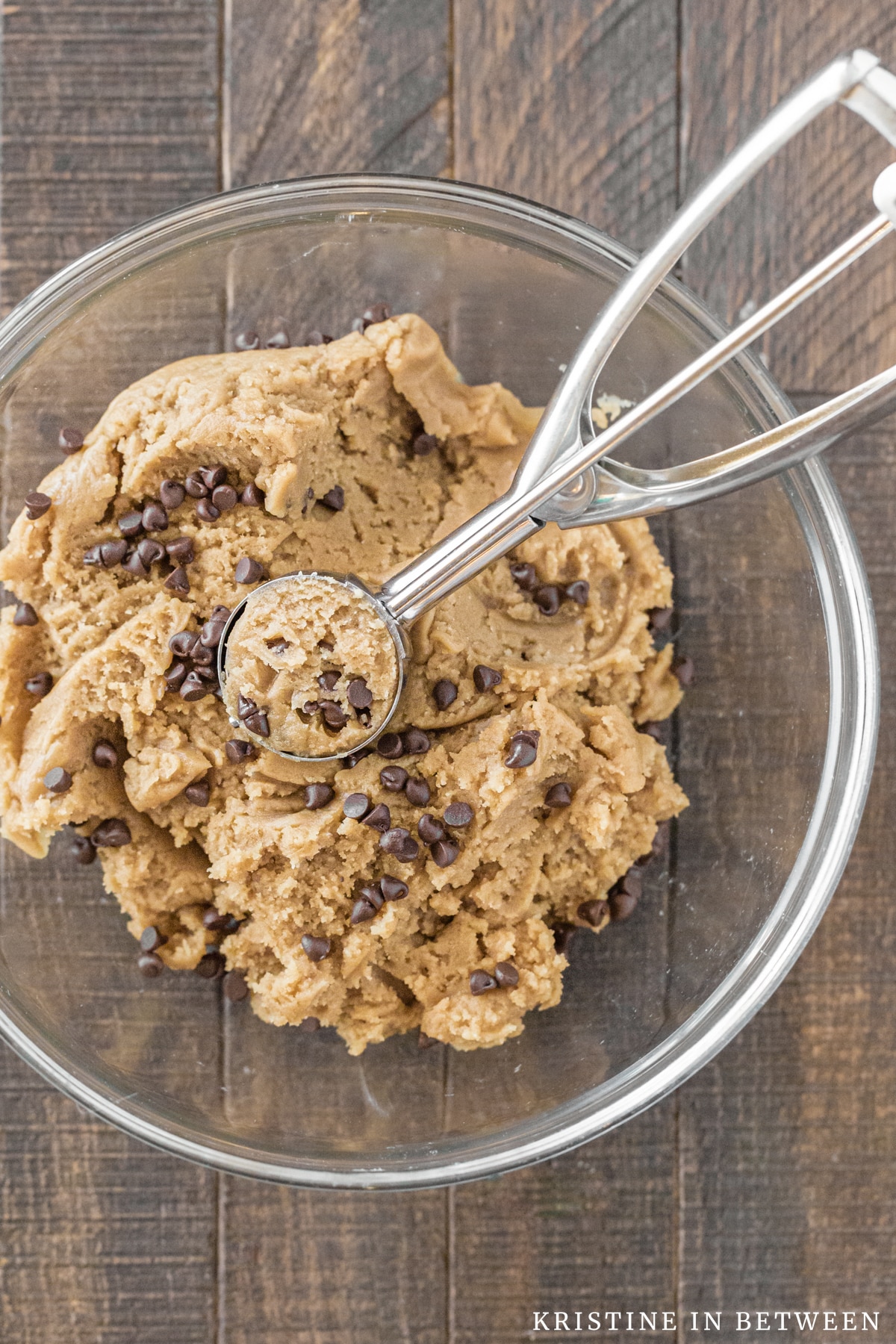 Basic cookie dough with chocolate chips in a glass bowl with a cookie scoop.