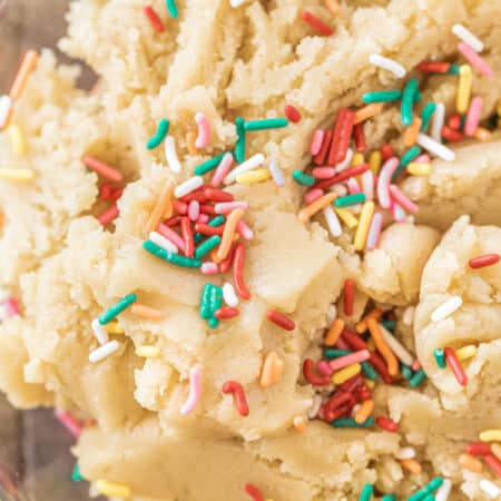 Sugar cookie dough in a glass bowl with sprinkles on top.
