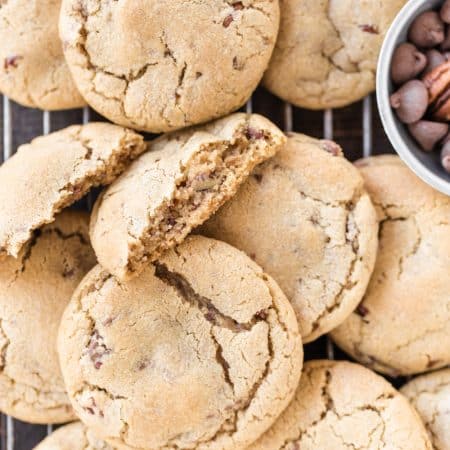 A bunch of cookies on a wooden board one broken in half showing the inside