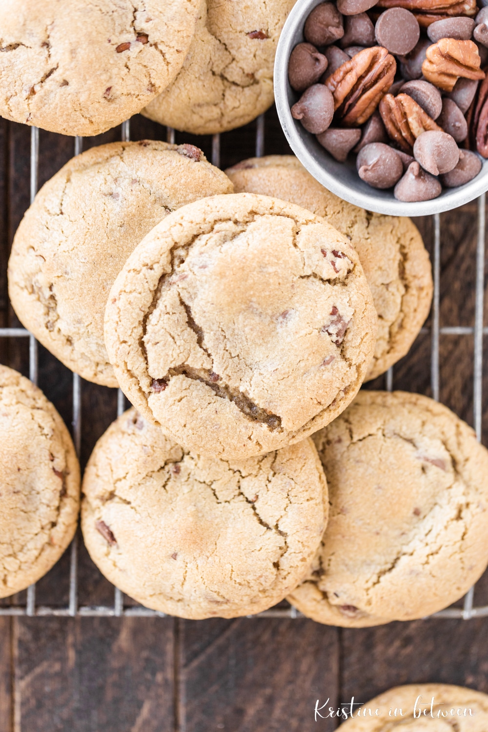 Chocolate chip pecan cookies sitting on a rack with a small bowl of chocolate chips and pecans