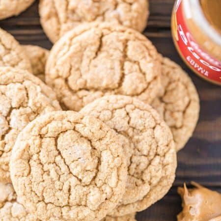 A stack of cookies with a jar of cookie butter and a knife sitting next to them.