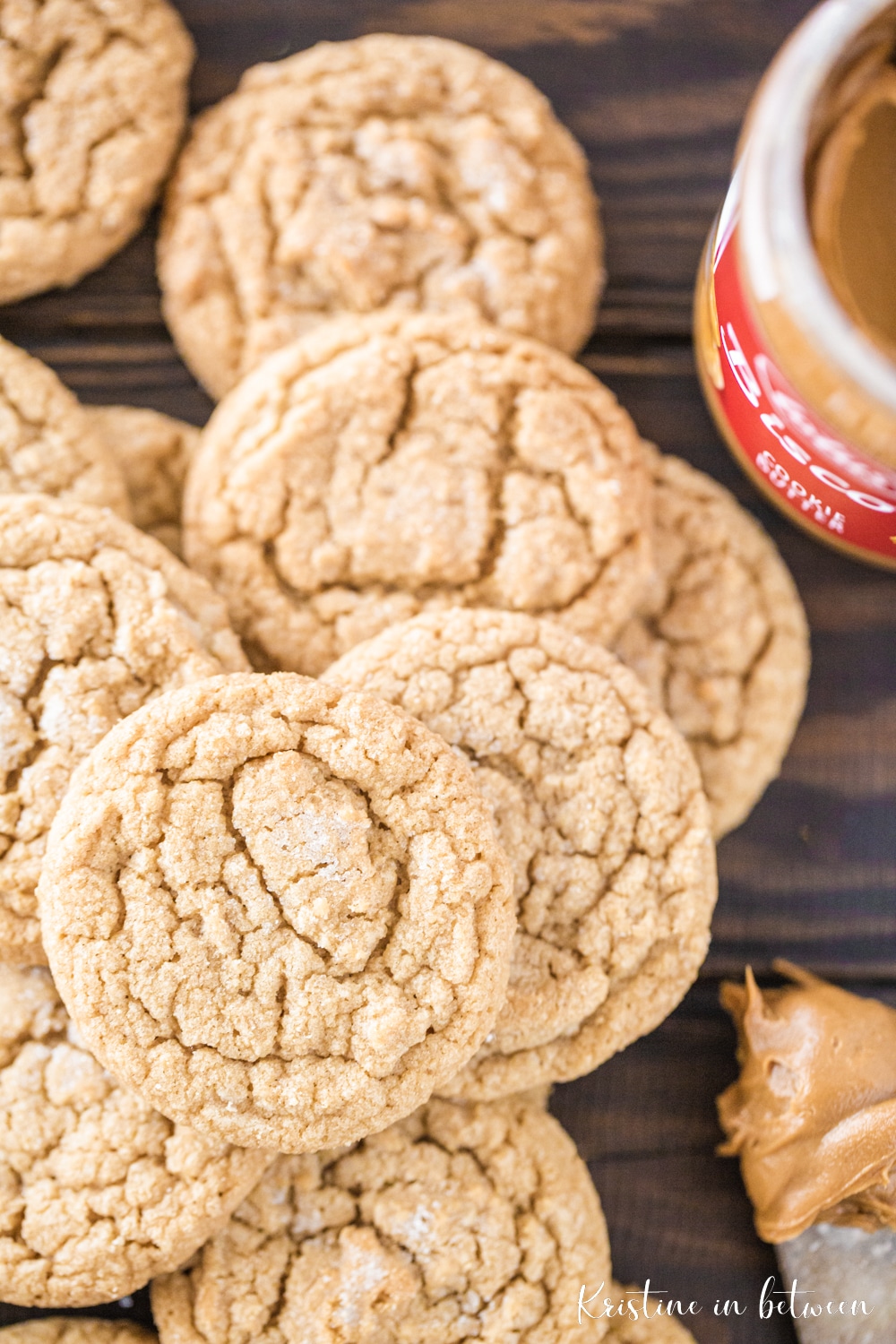 A stack of cookies with a jar of cookie butter and a knife sitting next to them.