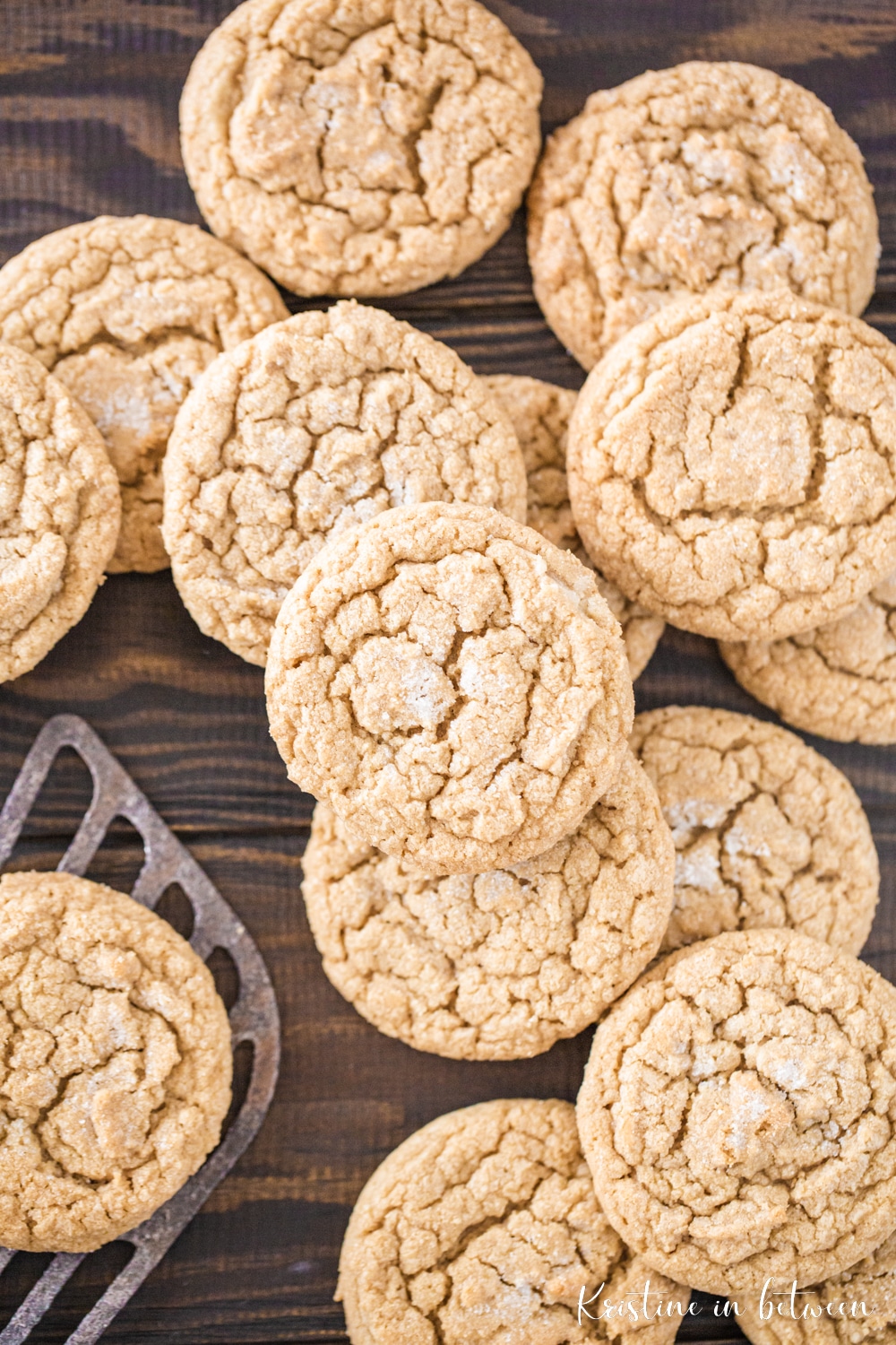 Cookies spread out on a wooden table with one sitting on an antique spatula.