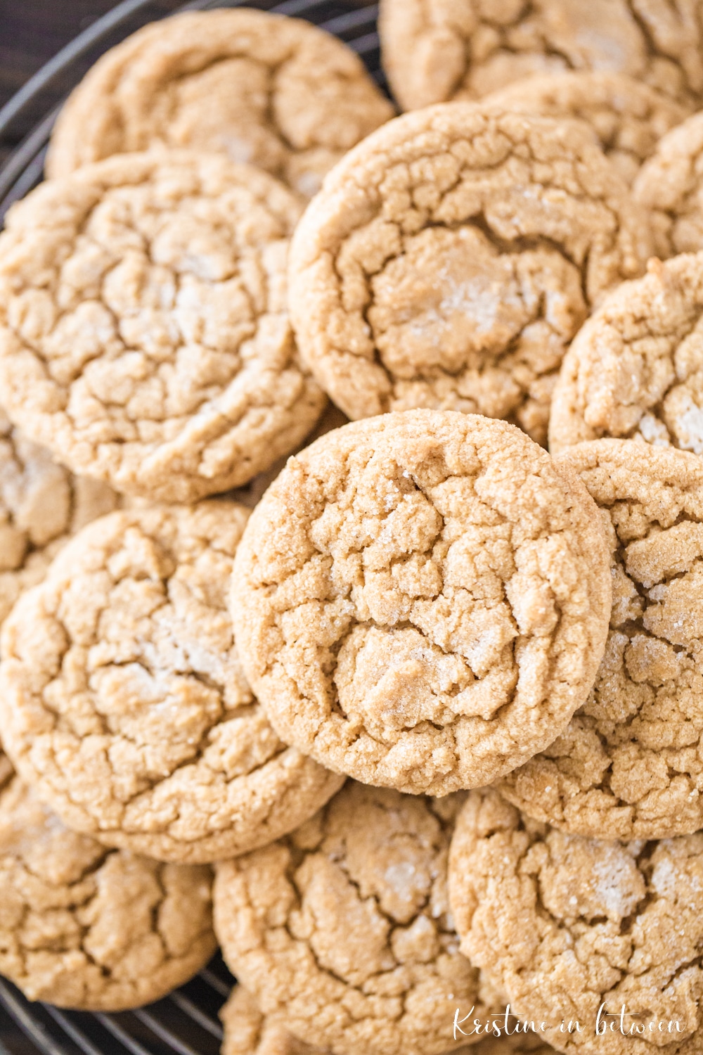 A large stack of cookies with crinkle tops sitting on a wire backing rack.