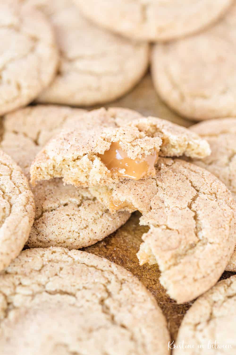 Cookies piled up with the top one split in half to show caramel dripping out of the cookie.