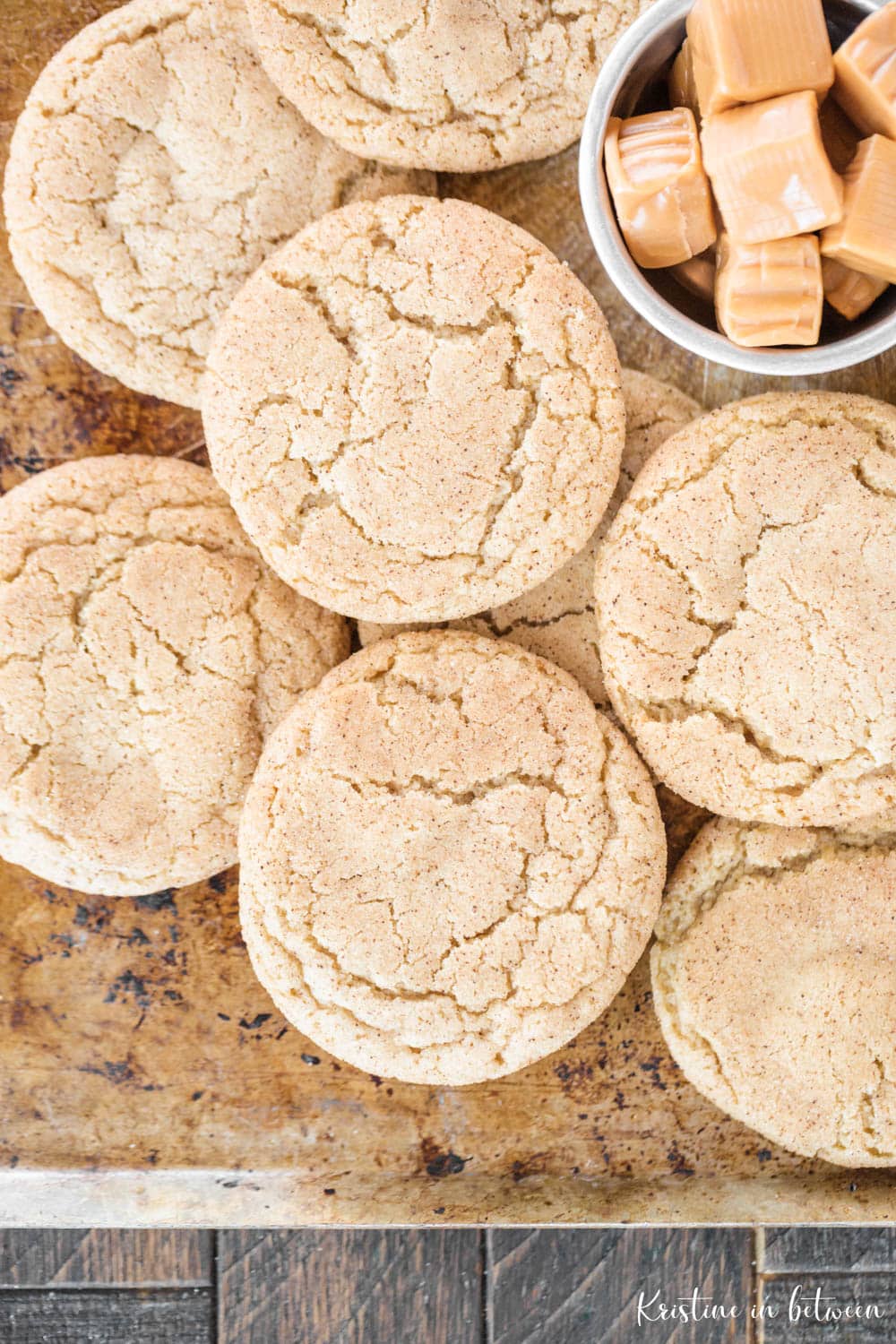 Cookies laying on a baking sheet with a small bowl of unwrapped caramels.