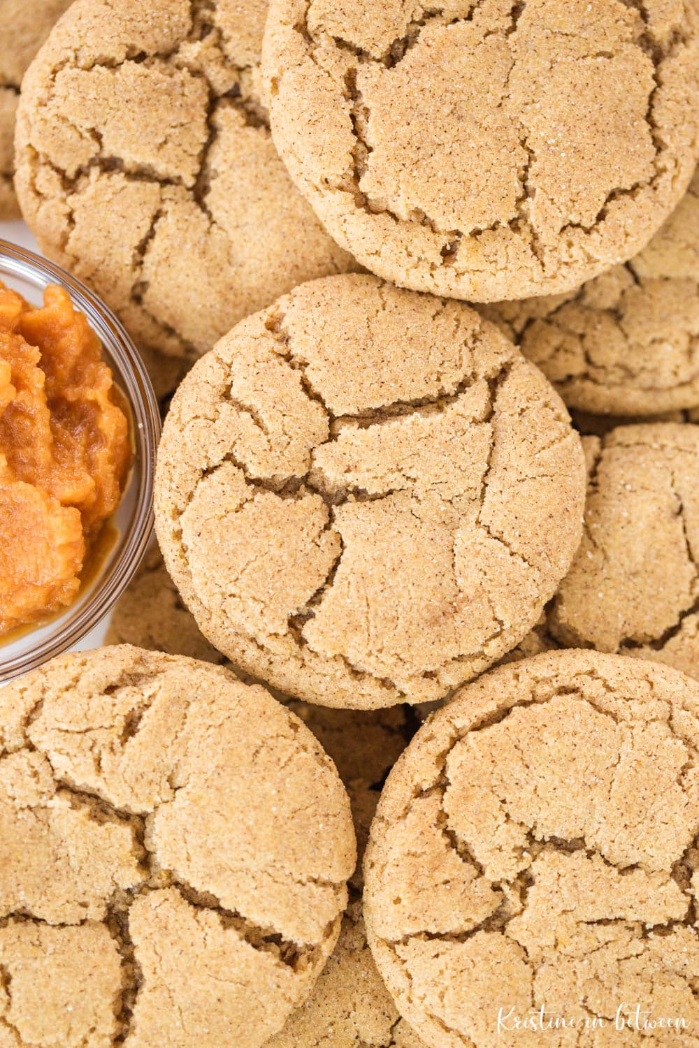Cookies piled up with a small bowl of pumpkin puree nestled with them.