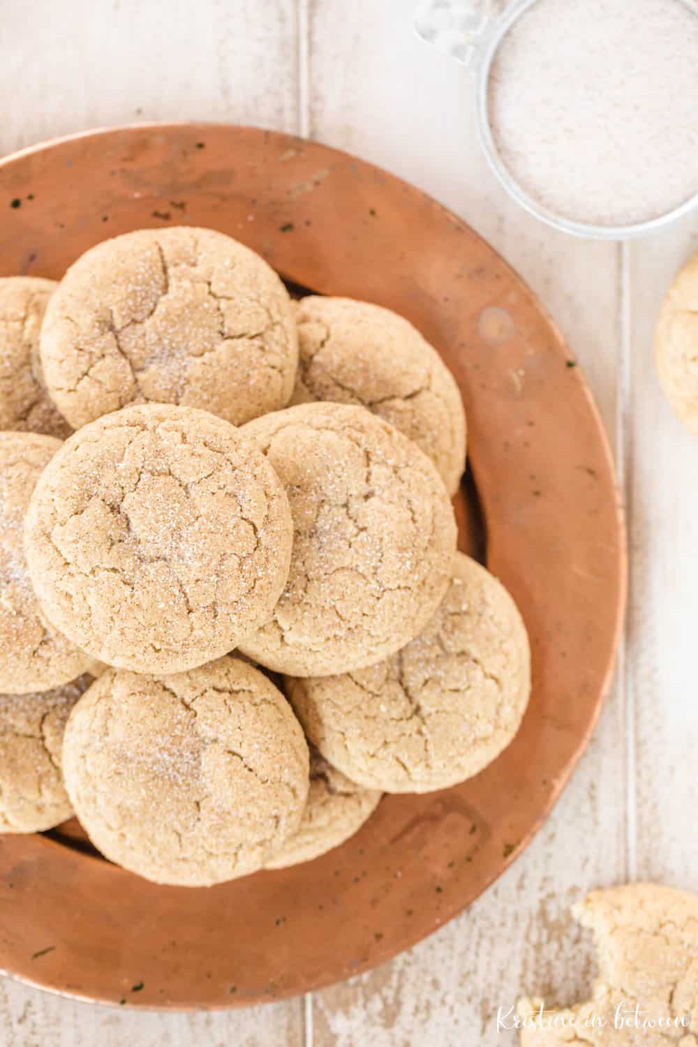 Cookies laying on a copper plate with a small bowl of cinnamon and sugar.