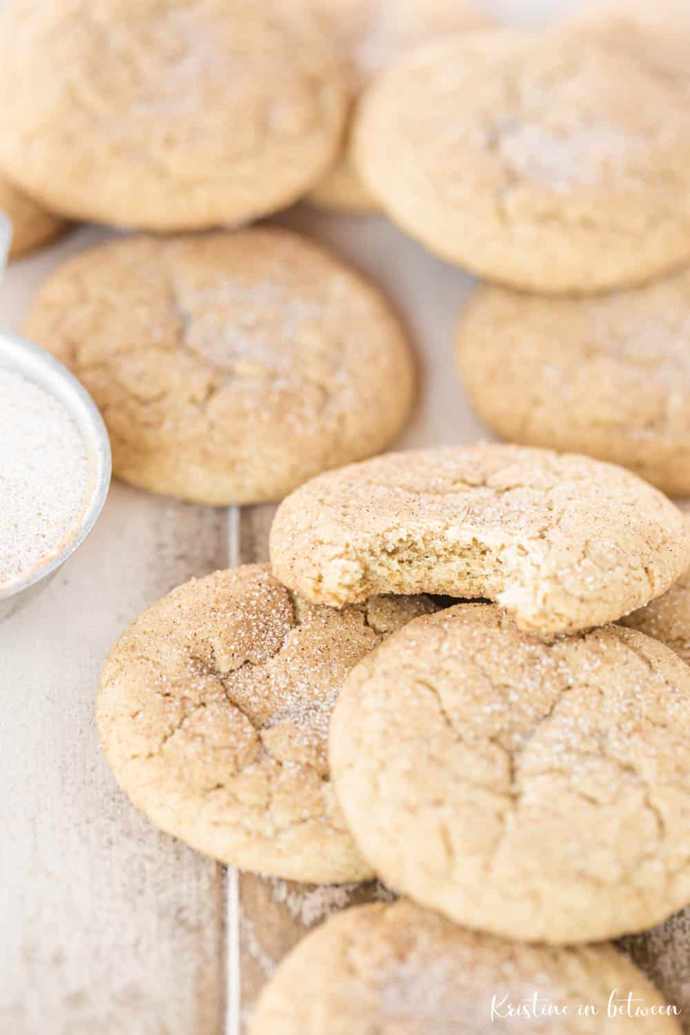 Cookies laying on a wooden table and one has a bite out of it, showing the inside of the cookie.