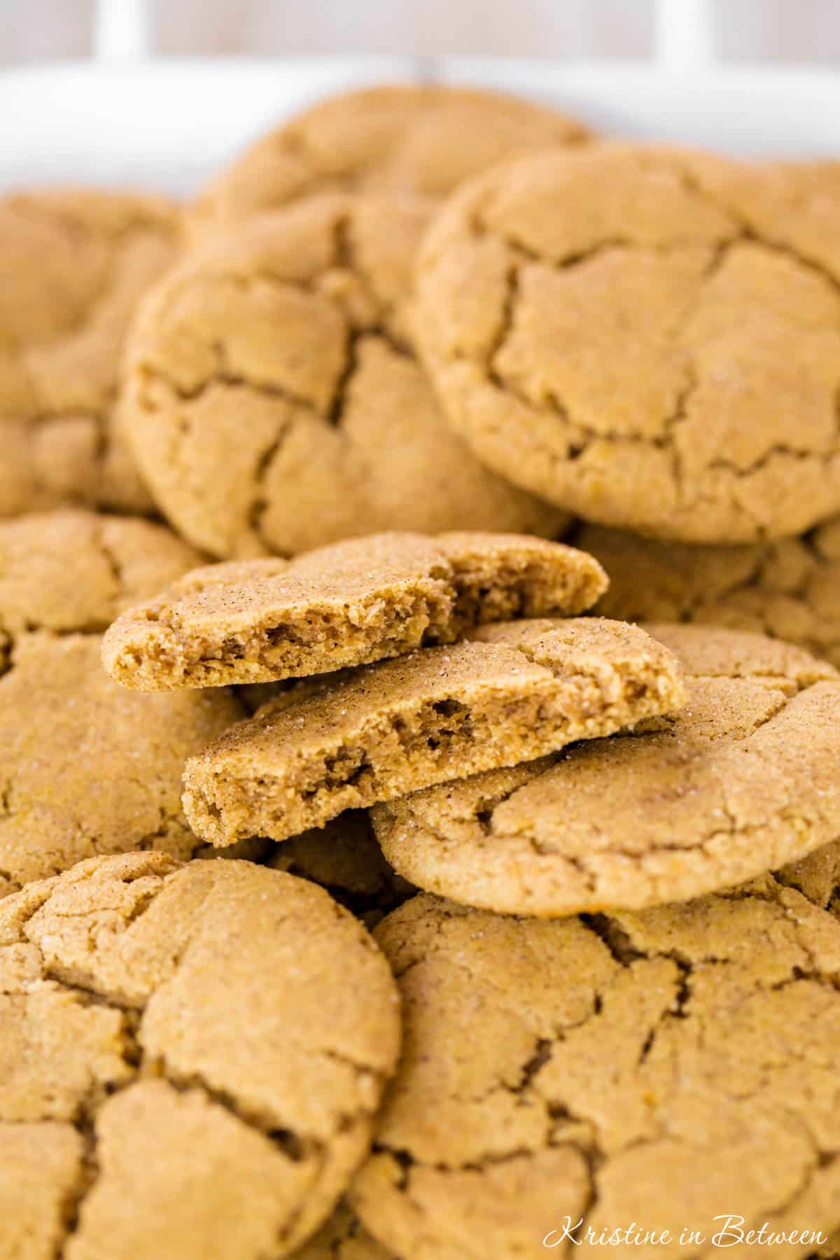 A cookie broken in half laying on top of other cookies to show detail.