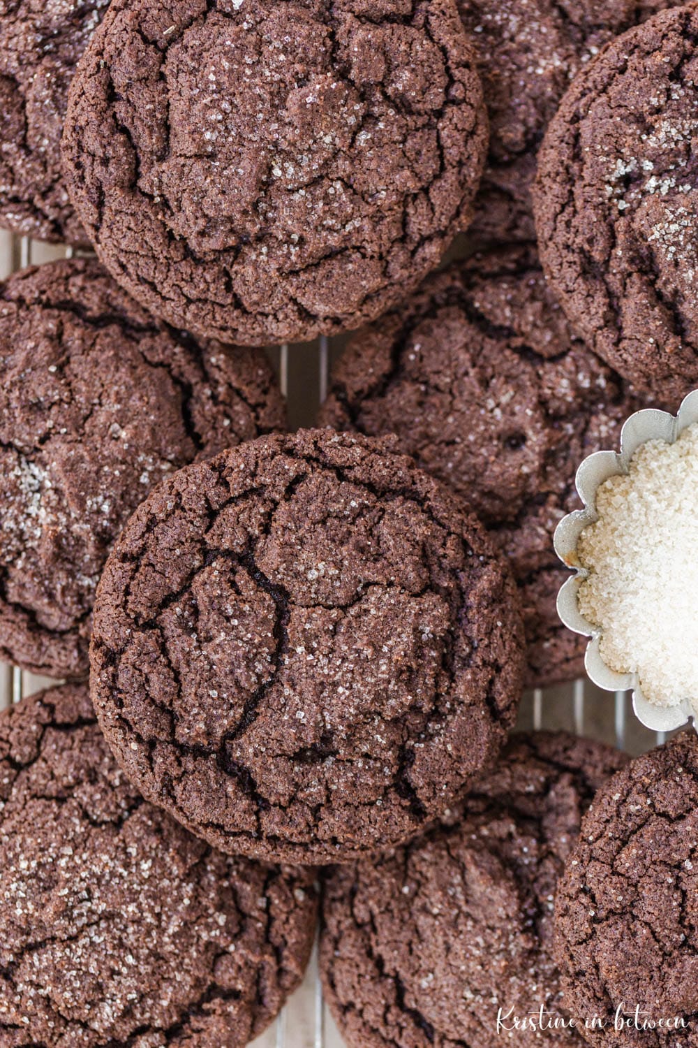 Cookies laying on a wire baking rack with a small bowl of sugar.