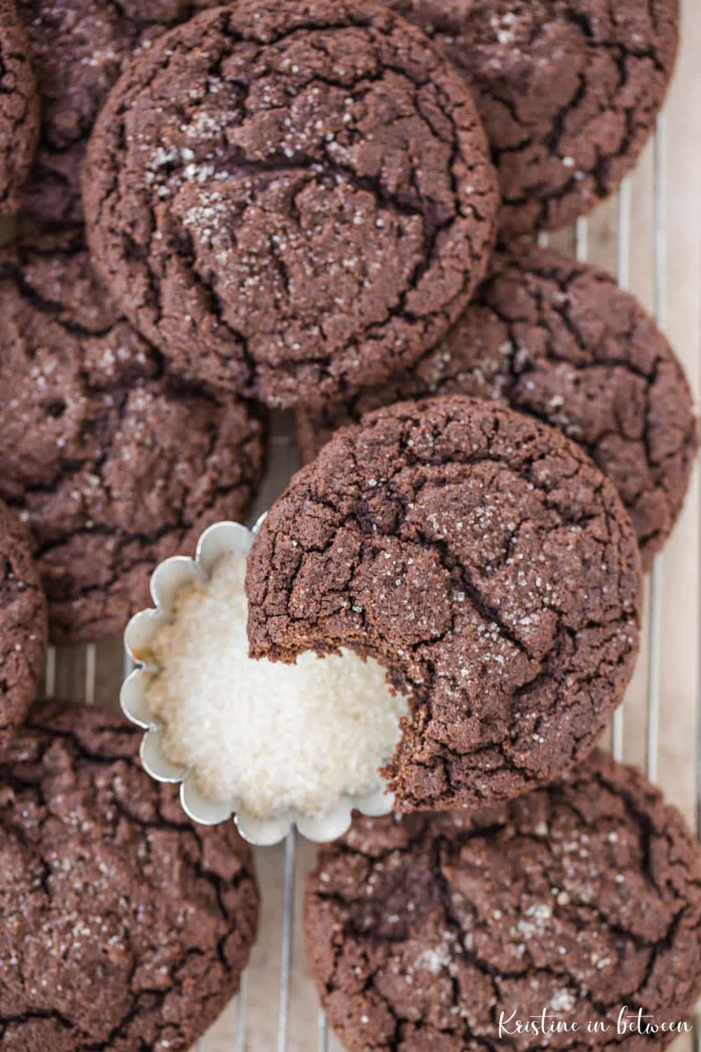 Cookies laying on a wire rack with a small bowl of sugar.