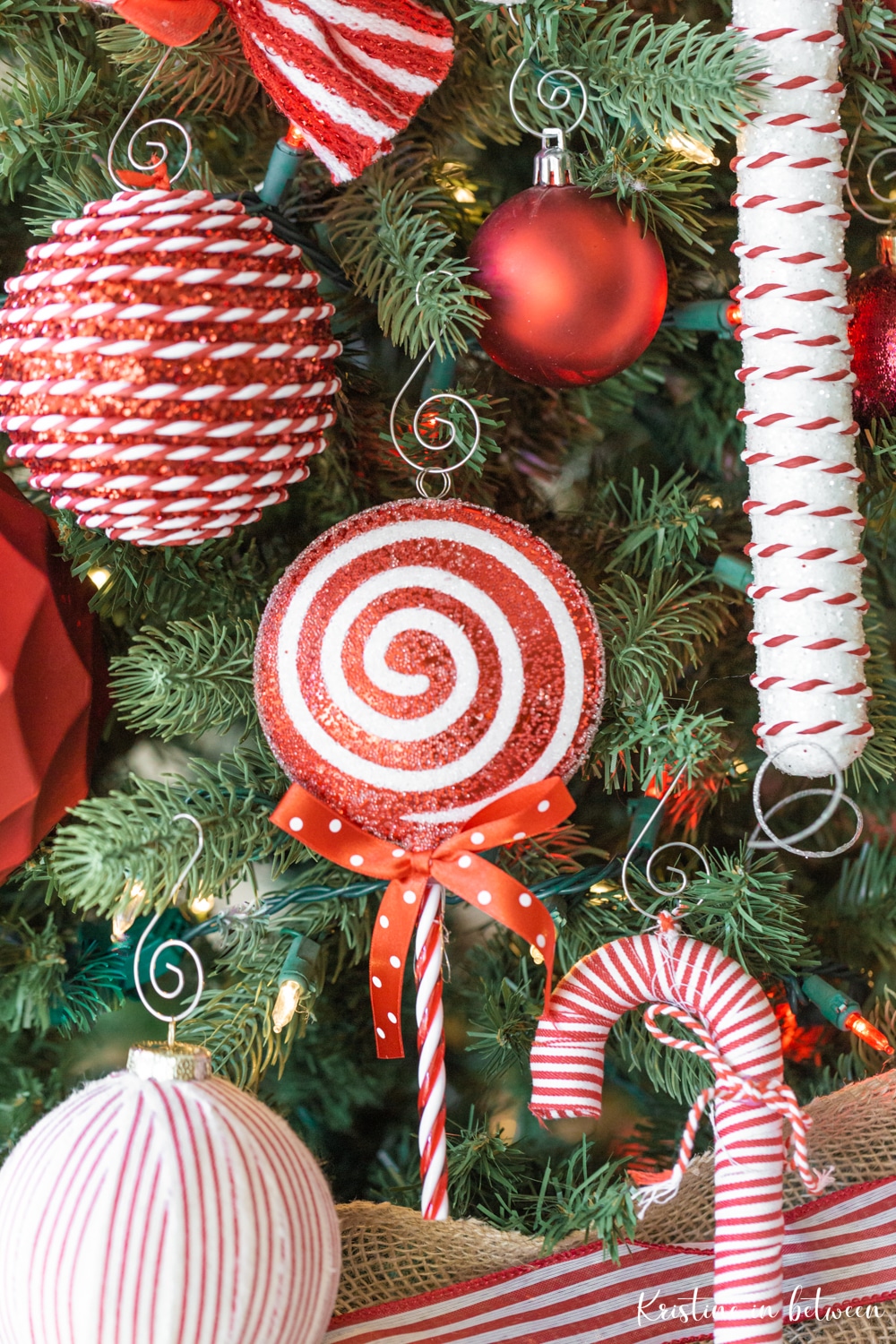 Red and white candy cane ornaments hanging on a Christmas tree.