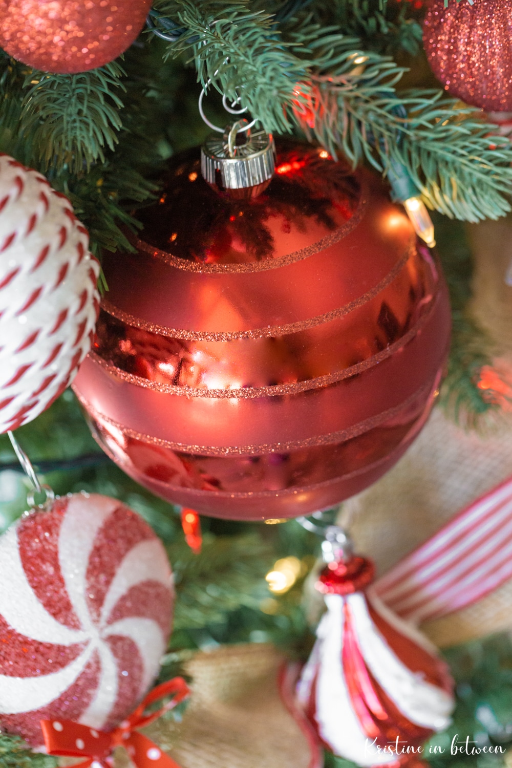 A red ornament hanging on a Christmas tree.