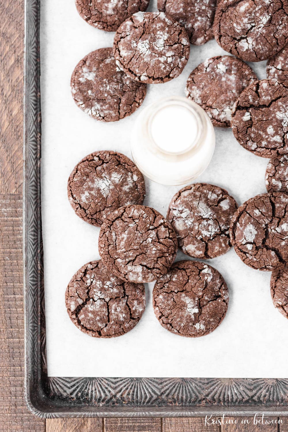 Cookies laying on a cookie sheet with a jar of milk nestled with them.