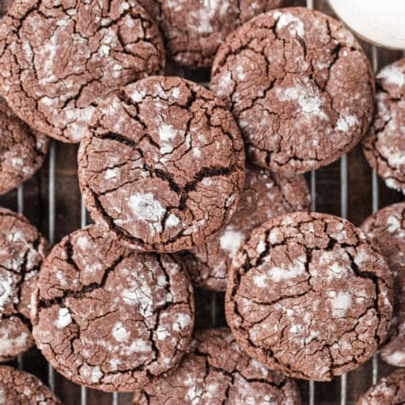 Cookies laying on a wire rack with a jar of milk with them.
