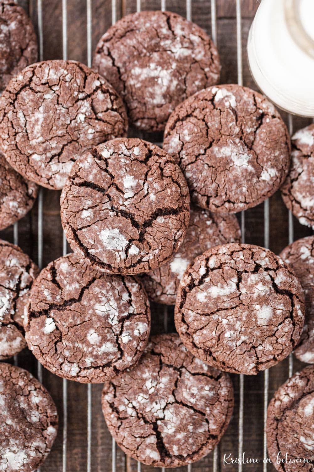 Cookies laying on a wire rack with a jar of milk with them.