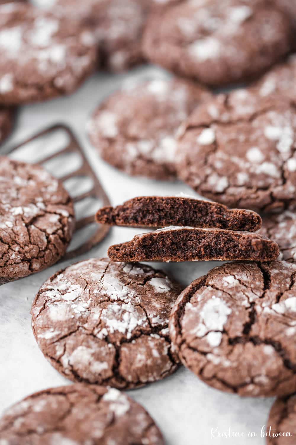 Cookies laying on parchment paper with one broken in half to show the inside of the cookie.