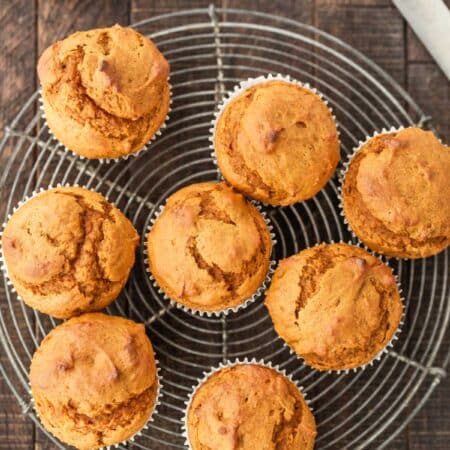 Pumpkin muffins sitting on a wire cooling rack with an antique knife next to them.