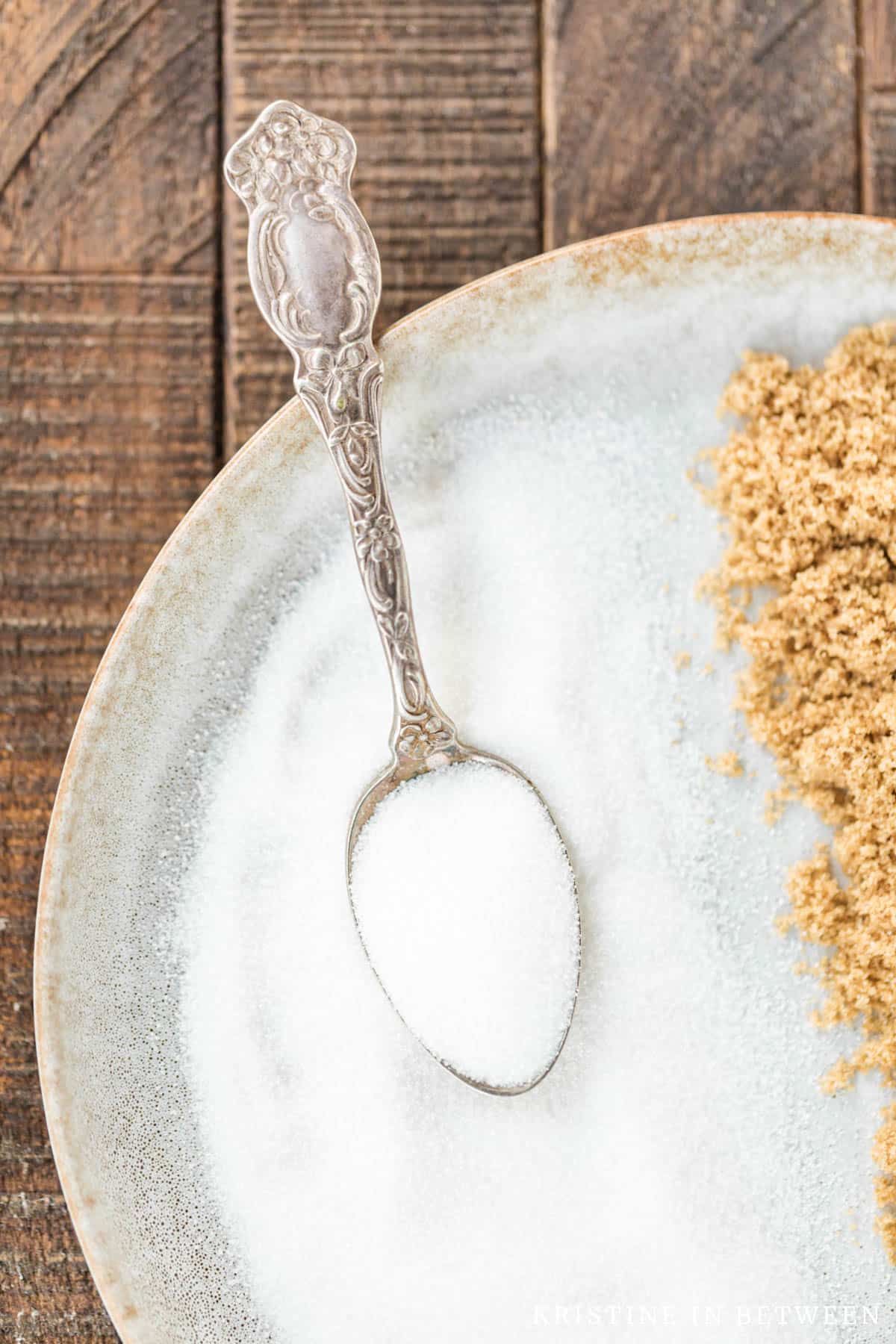 A plate filled with white sugar and an antique spoon in it.