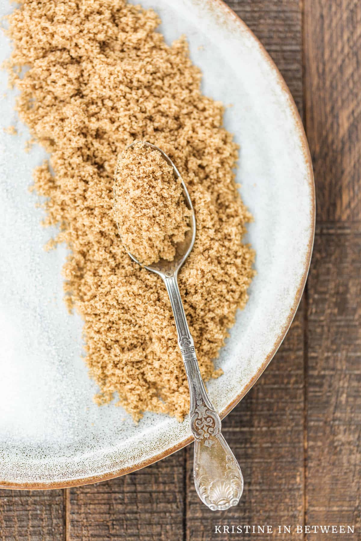 A plate filled with brown sugar and an antique spoon in it.