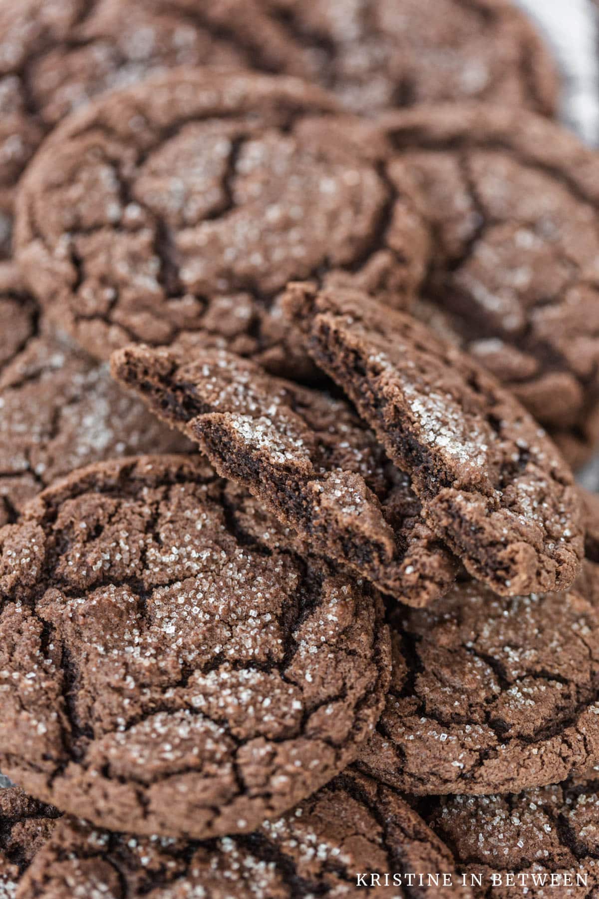 Chocolate cookies stacked up with one on top that's cut in half to show the inside of the cookie.