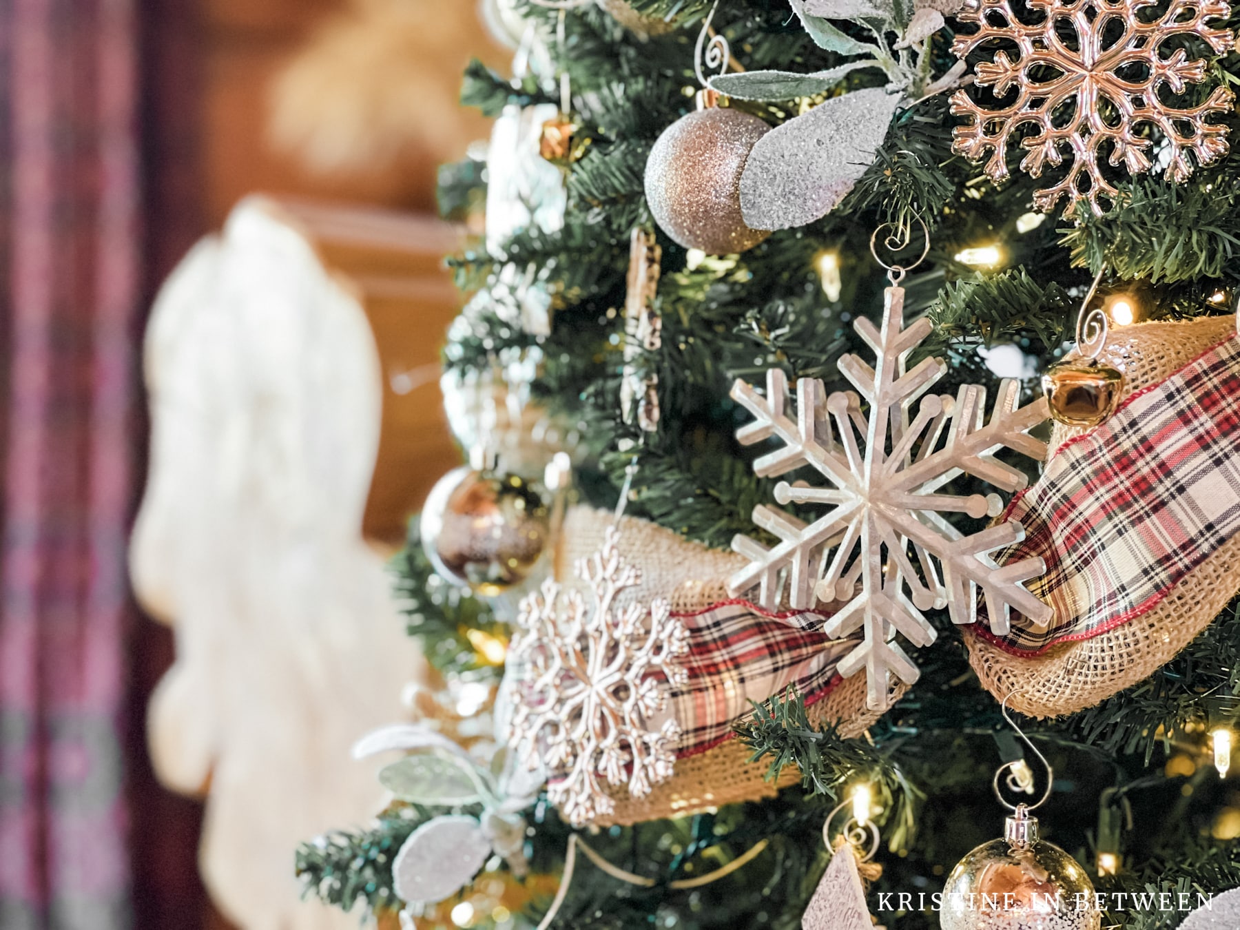 A Christmas tree decorated with plaid ribbon and silver snowflakes.