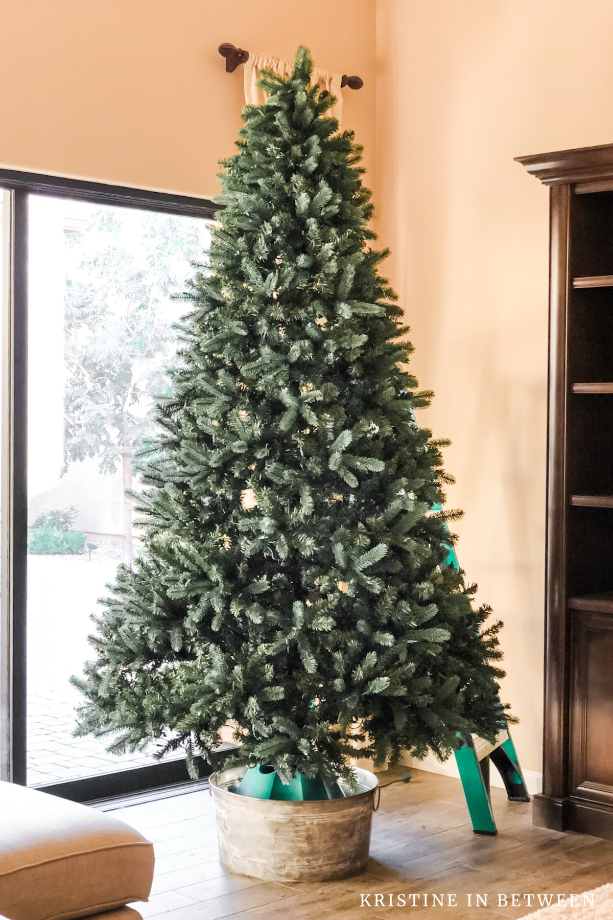 An undecorated Christmas tree standing in a bucket in a family room.