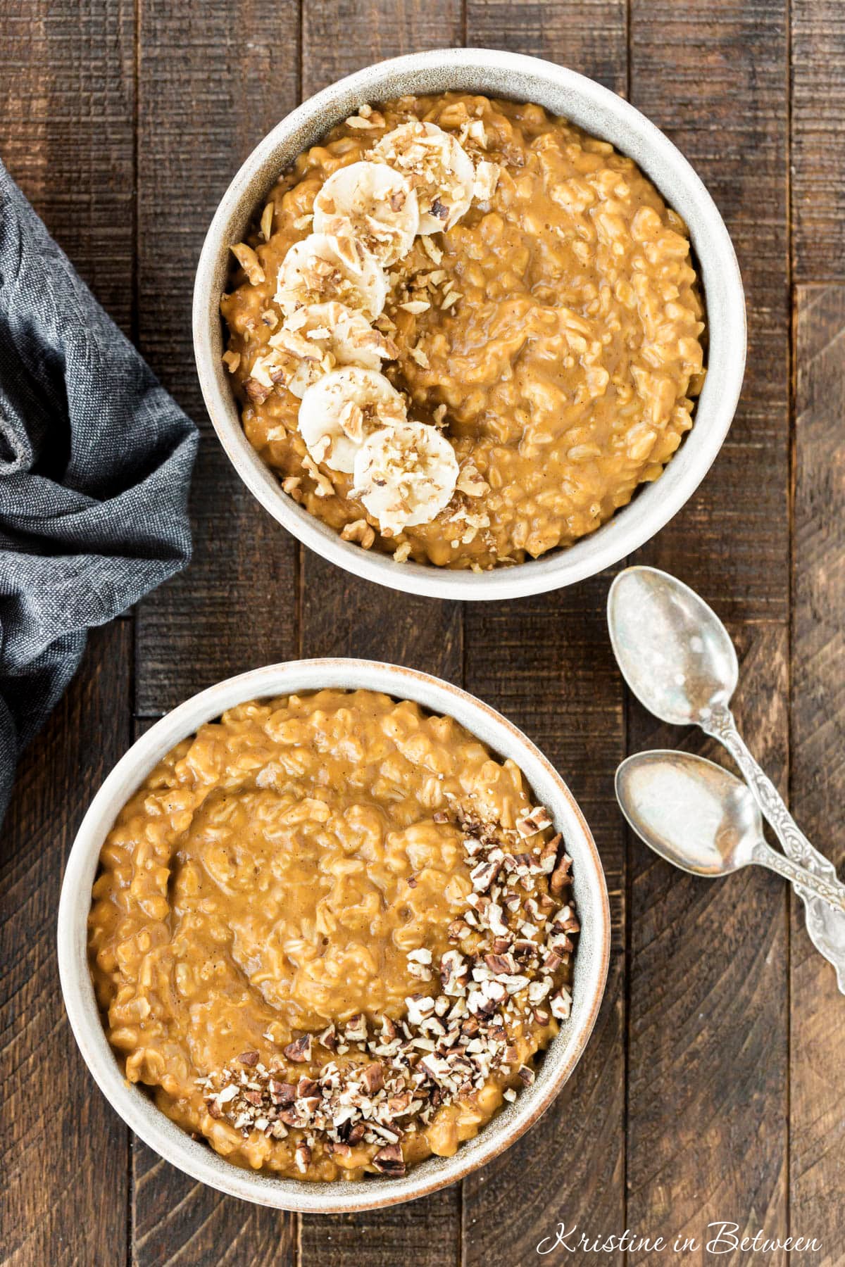 Two bowls of oatmeal, one with pecans and one with bananas and walnuts on top.