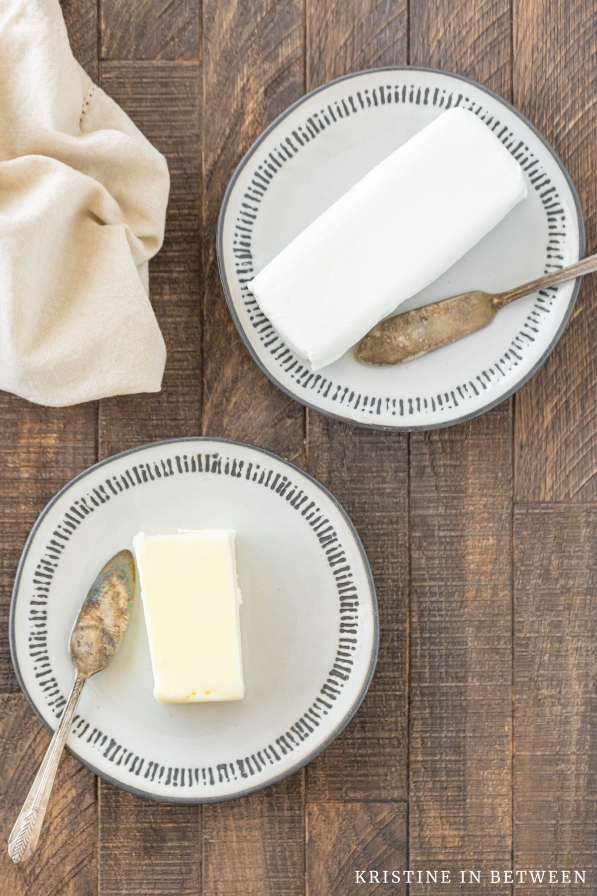Two plates, one with butter and one with shortening sitting with two butter knives.