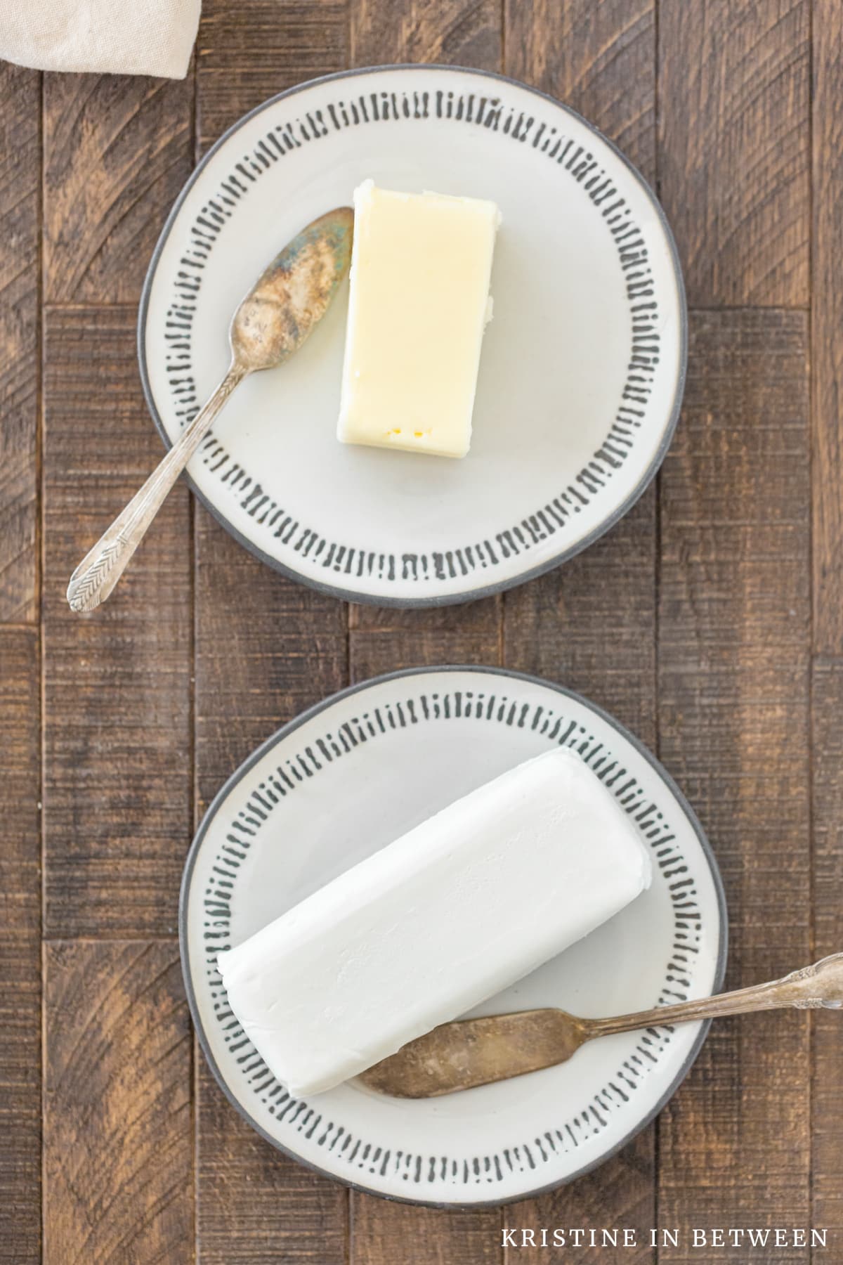 Two plates, one with butter and one with shortening sitting with two butter knives.