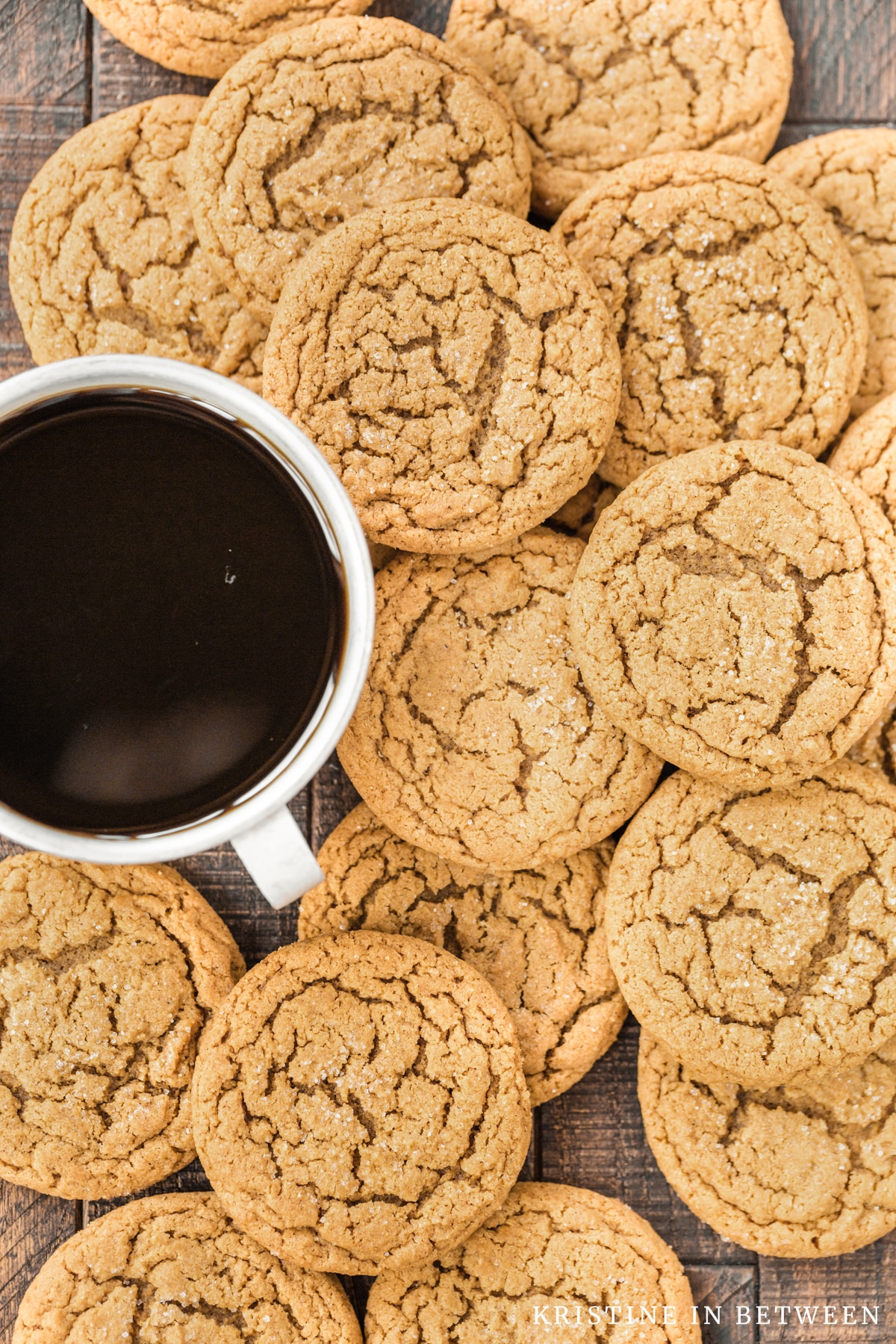 Cookies piled up on a wooden board with a cup of coffee nestled with them.