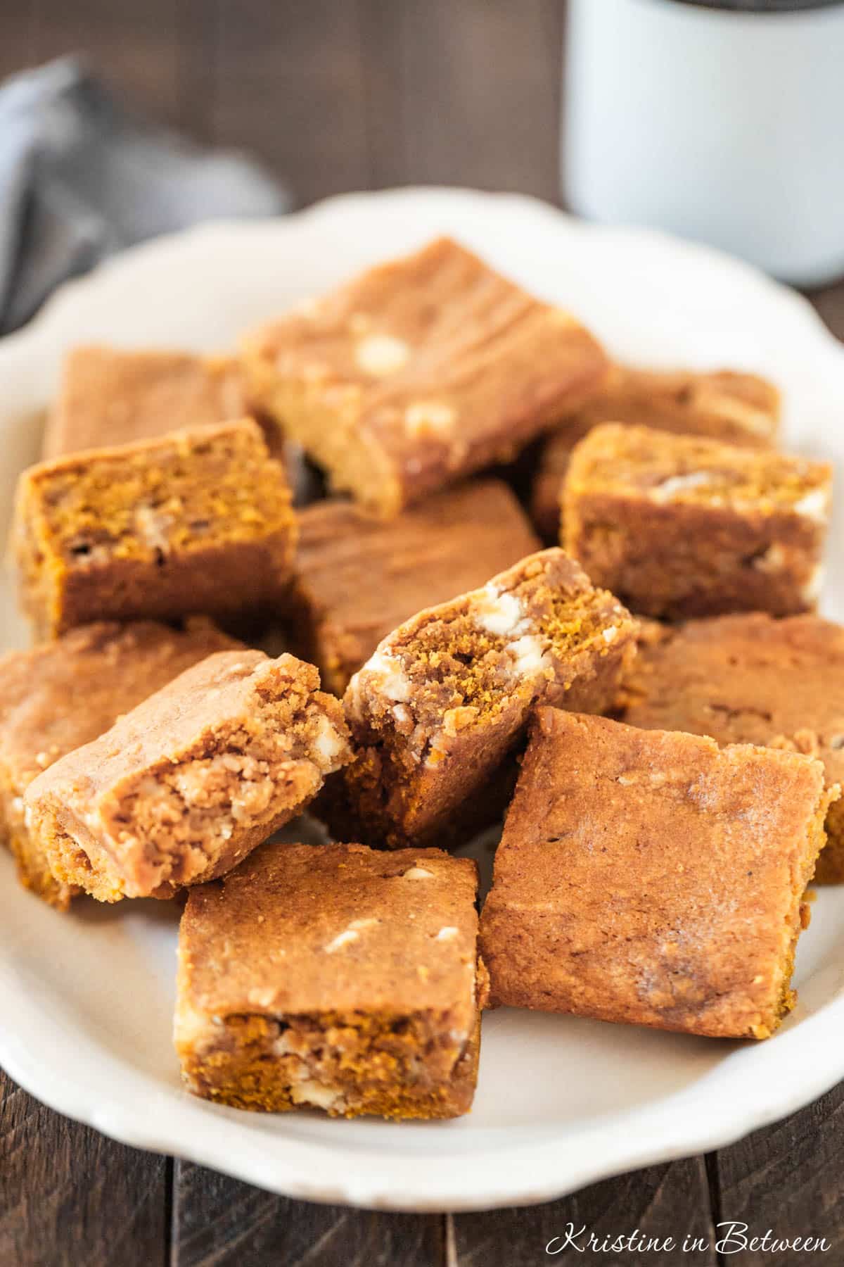 A pan of pumpkin blondies with white chocolate chips in them and a knife sitting next to them.