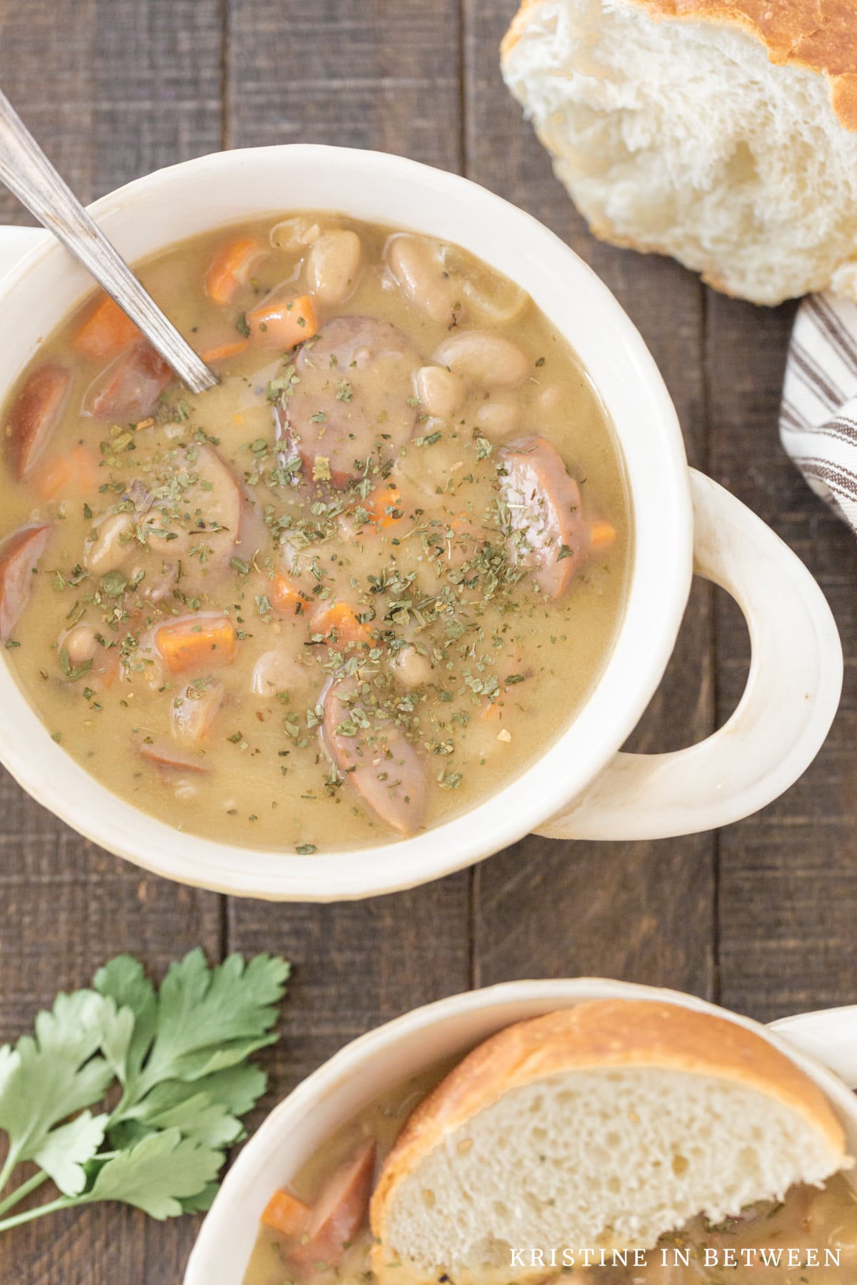 A bowl of soup with dried parsley on top  and a spoon in it.