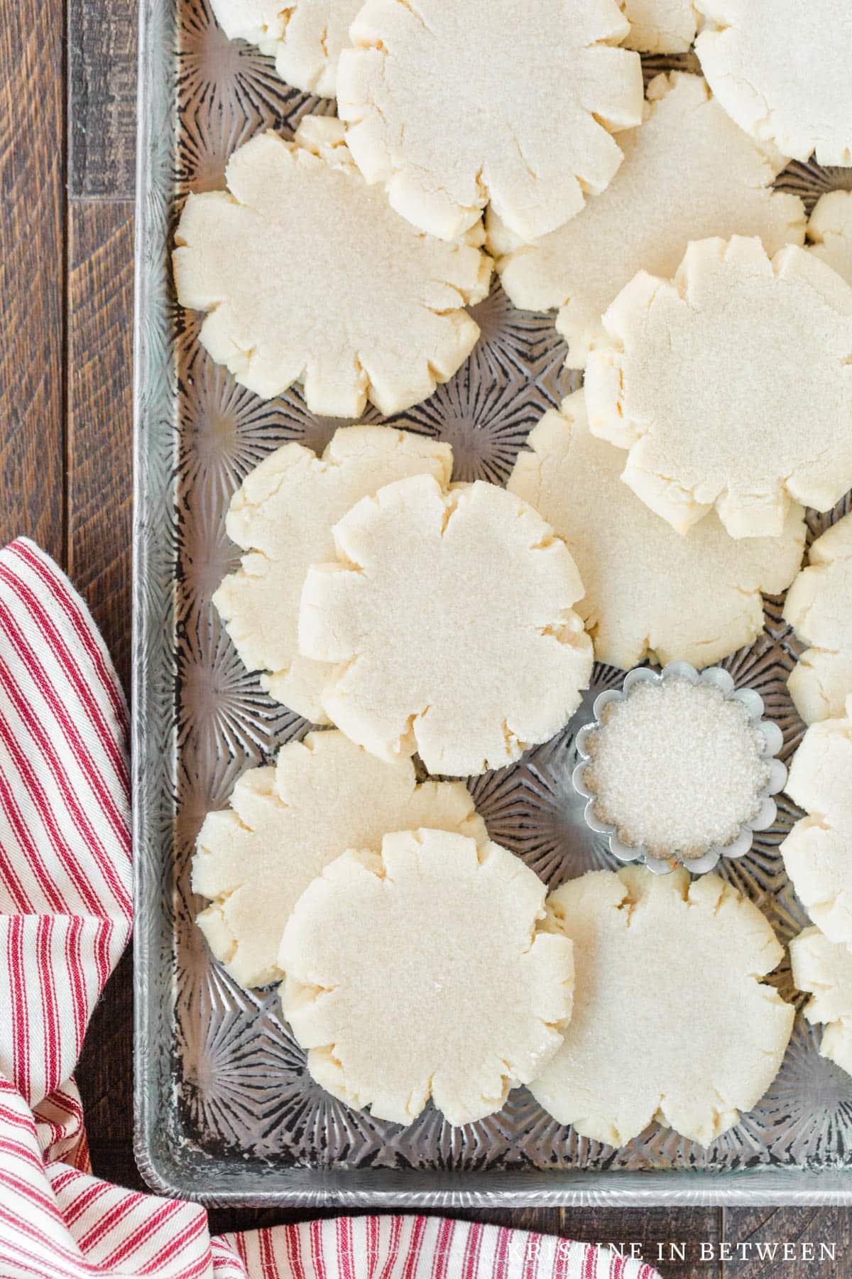 Cookies stacked up on an antique cookie sheet with a red striped napkin next to them.