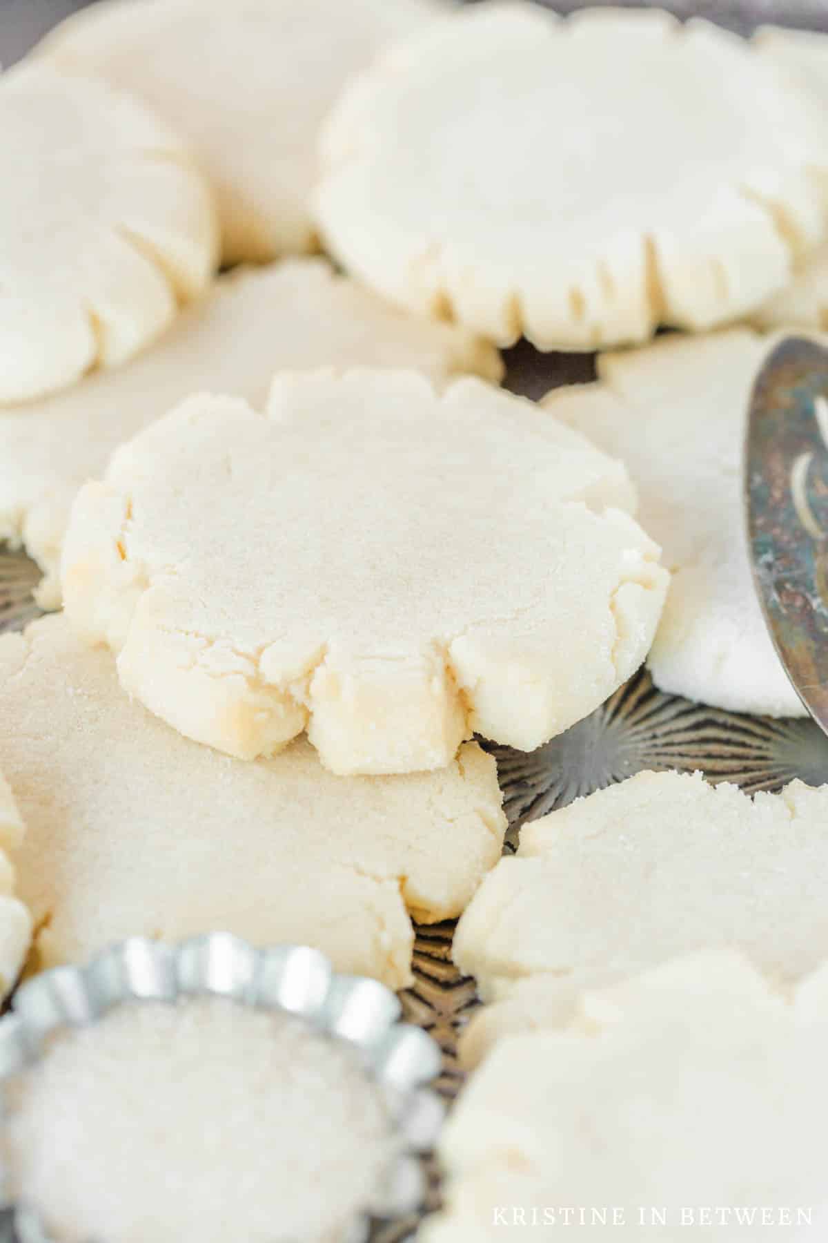 Sugar cookies stacked up on an antique cookie sheet with a red striped napkin next to them.