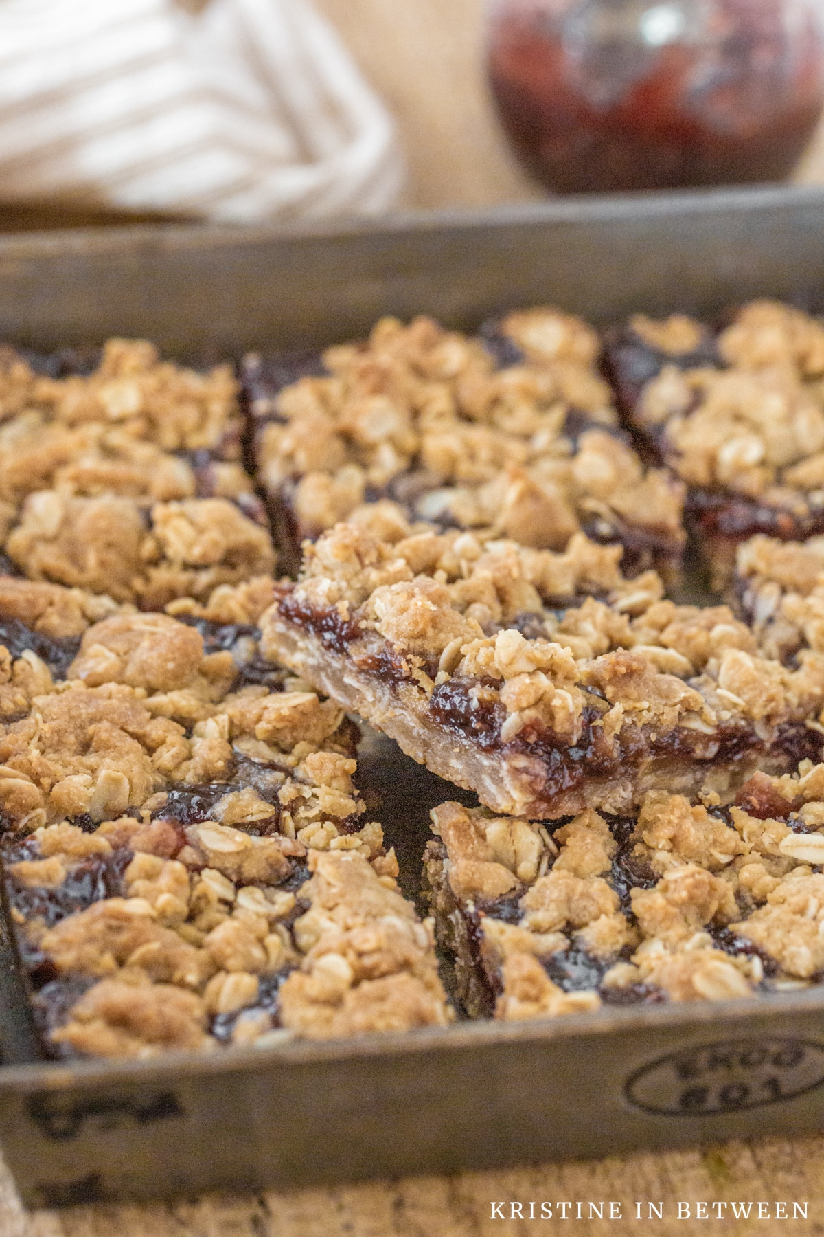 Raspberry jam crumble bars sitting in an antique baking pan with an old spatula.